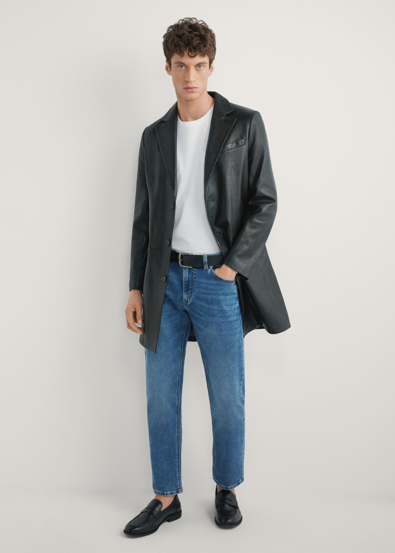 Pánsky čierny kožený kabát KURMS-0388-99(W26) - pohľad spredu na produkt na modelke, na svetlom pozadí. Viditeľná celá silueta.