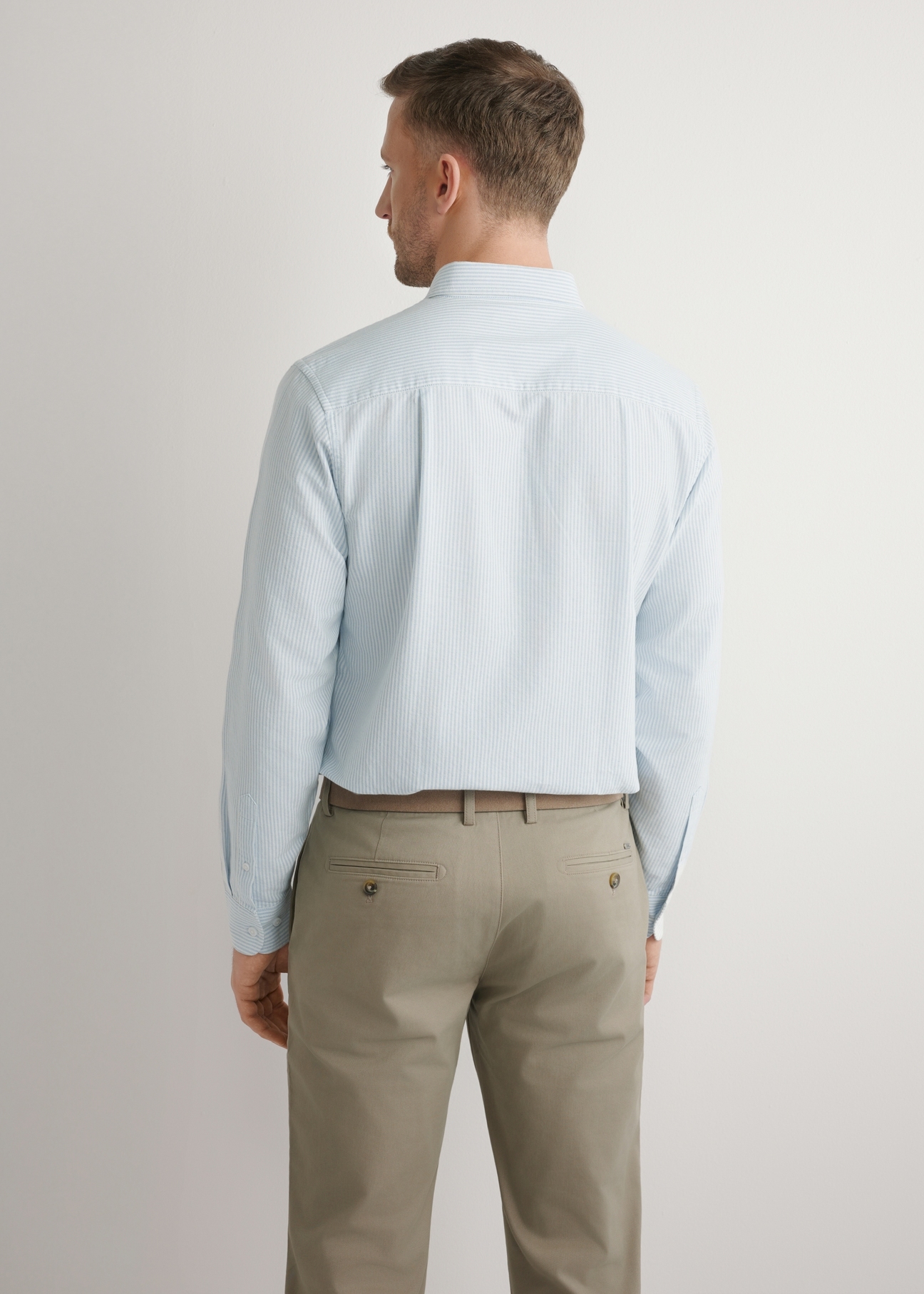 Pánska modrá bavlnená pruhovaná košeľa KOSMT-0354-7B(W26), pohľad na produkt zozadu na modelke. Viditeľná polovica siluety.