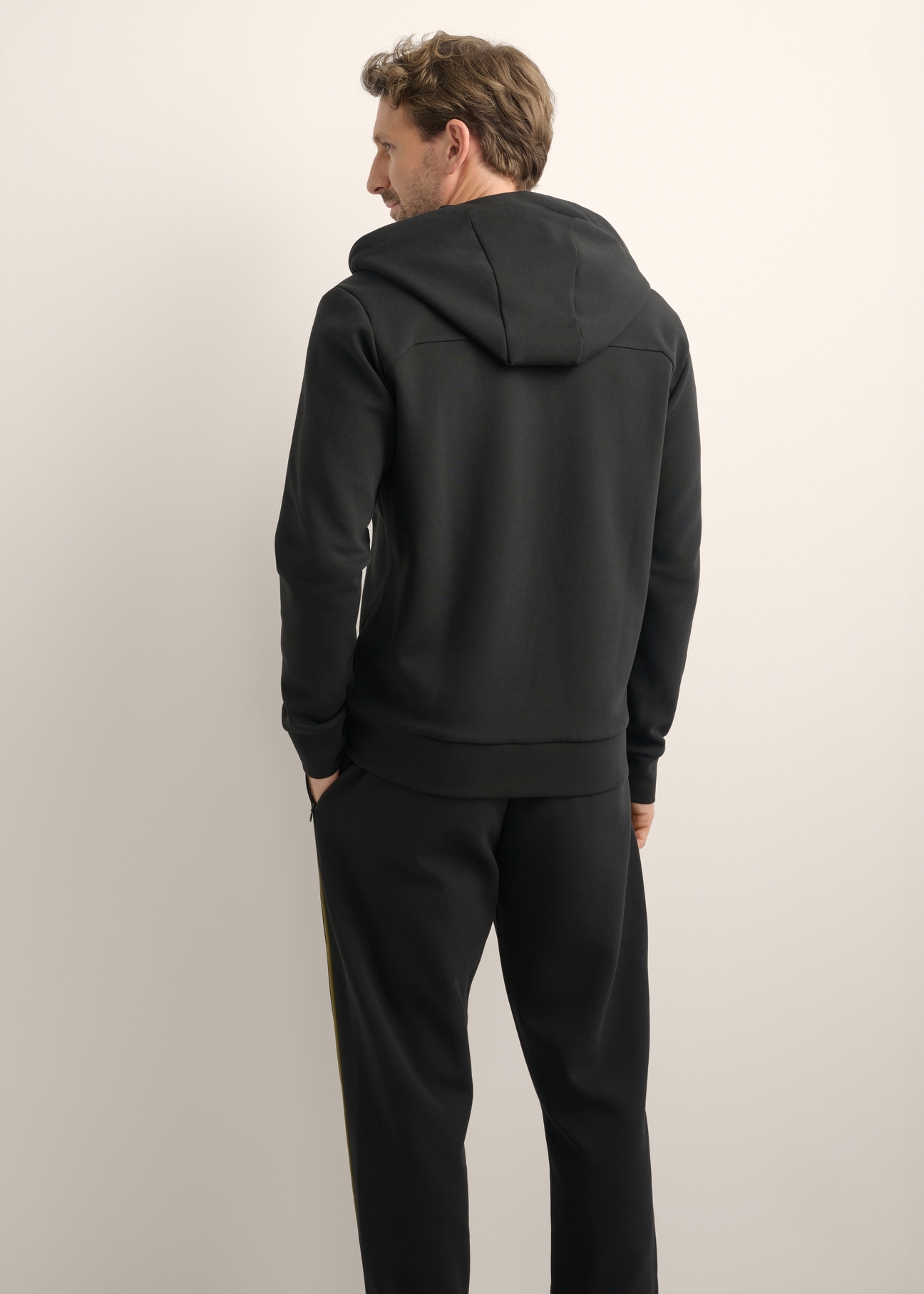 Pánska čierna mikina na zips BLZMT-0083-99(Z26), pohľad na produkt zozadu na modeli. Viditeľná polovica siluety.