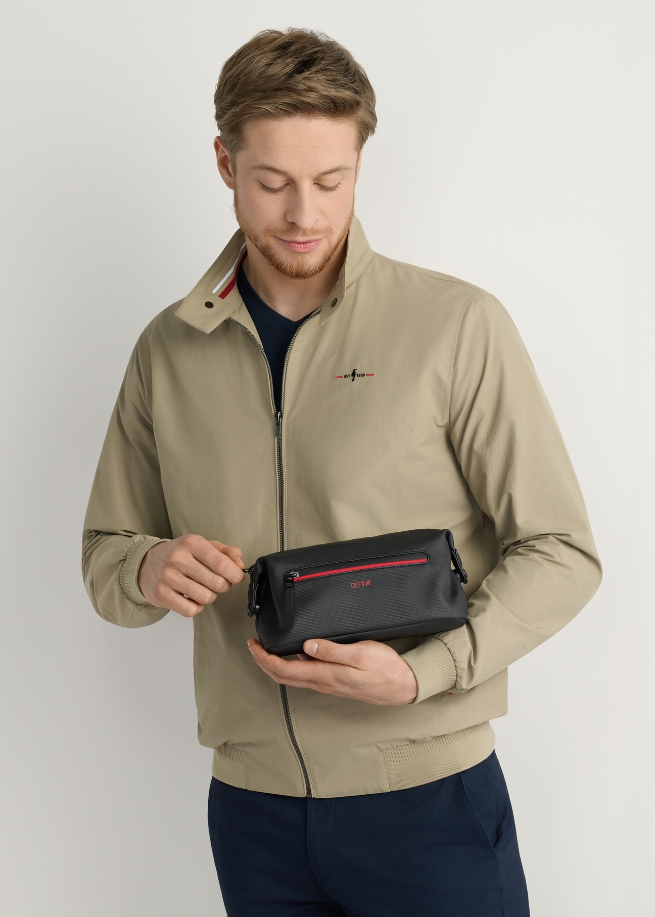 Čierna pánska kozmetická taška TORMN-0397-9J(W26), pohľad na produkt v ruke modelky, na svetlom pozadí.