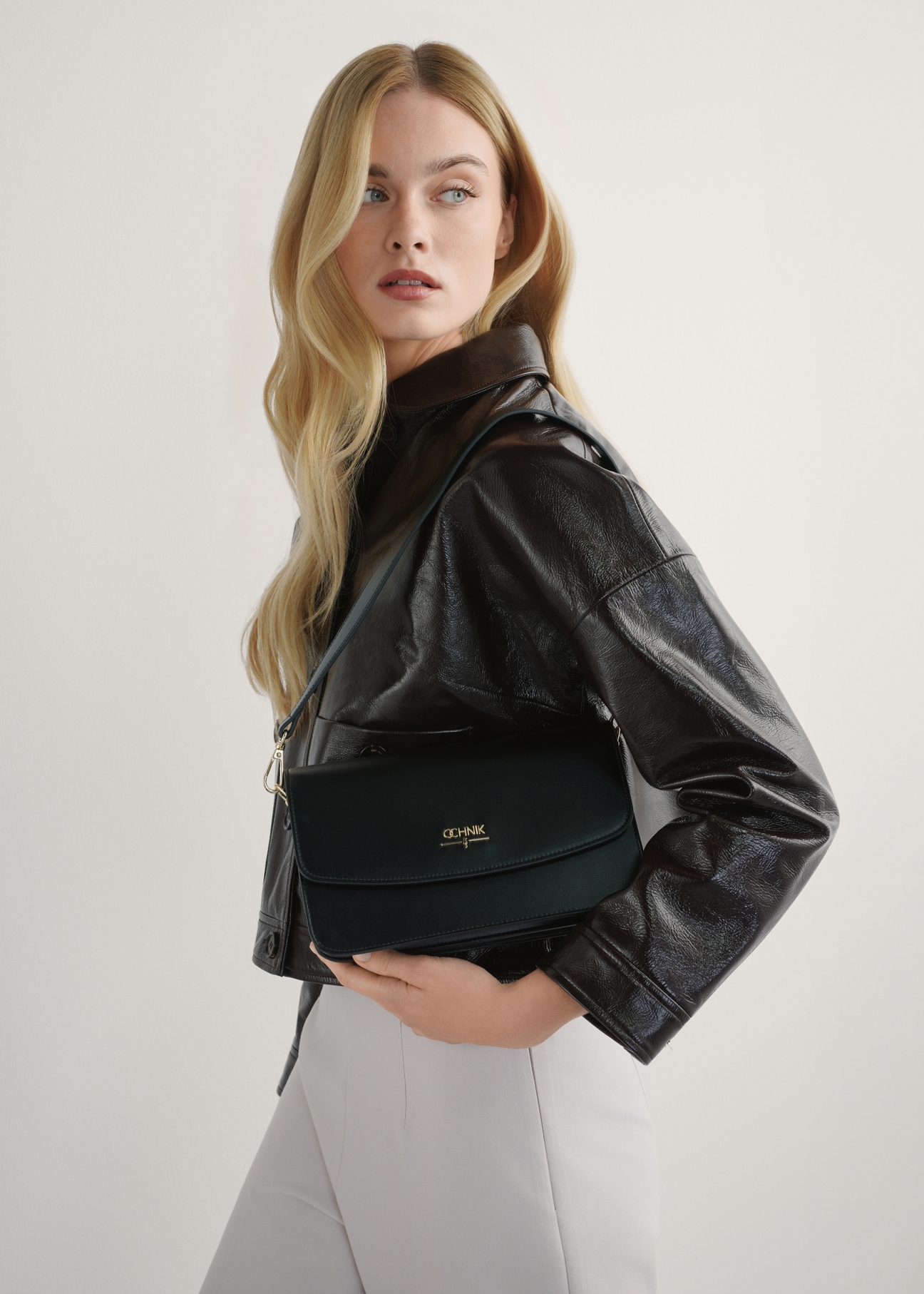 Čierna dámska kabelka z imitácie kože TOREC-1081-99(W26), pohľad na produkt v rukách modelky. Viditeľná polovica siluety.