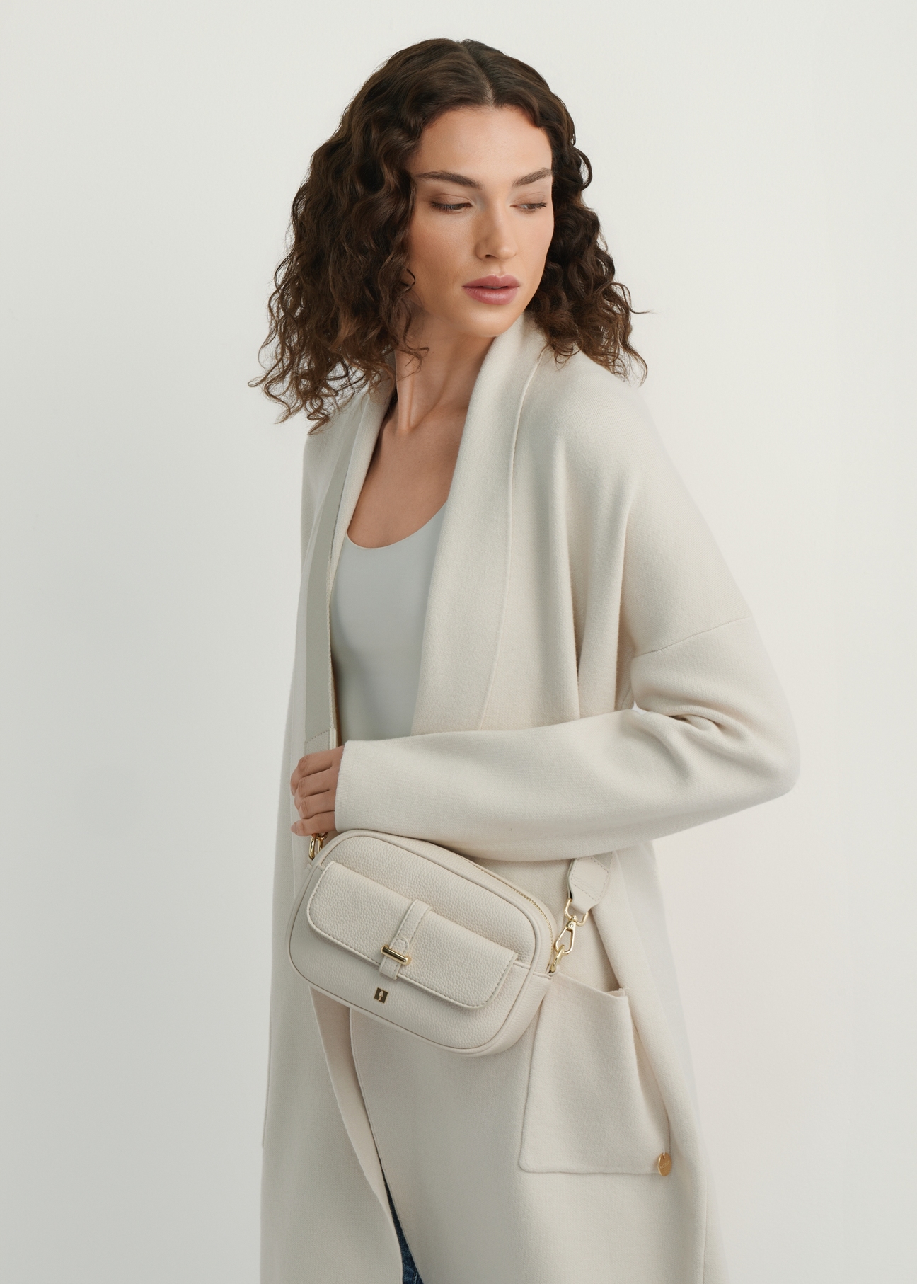 Malá krémová dámska kabelka TOREC-1174-0B(W26), pohľad na produkt na ramene modelky. Viditeľná polovica siluety.