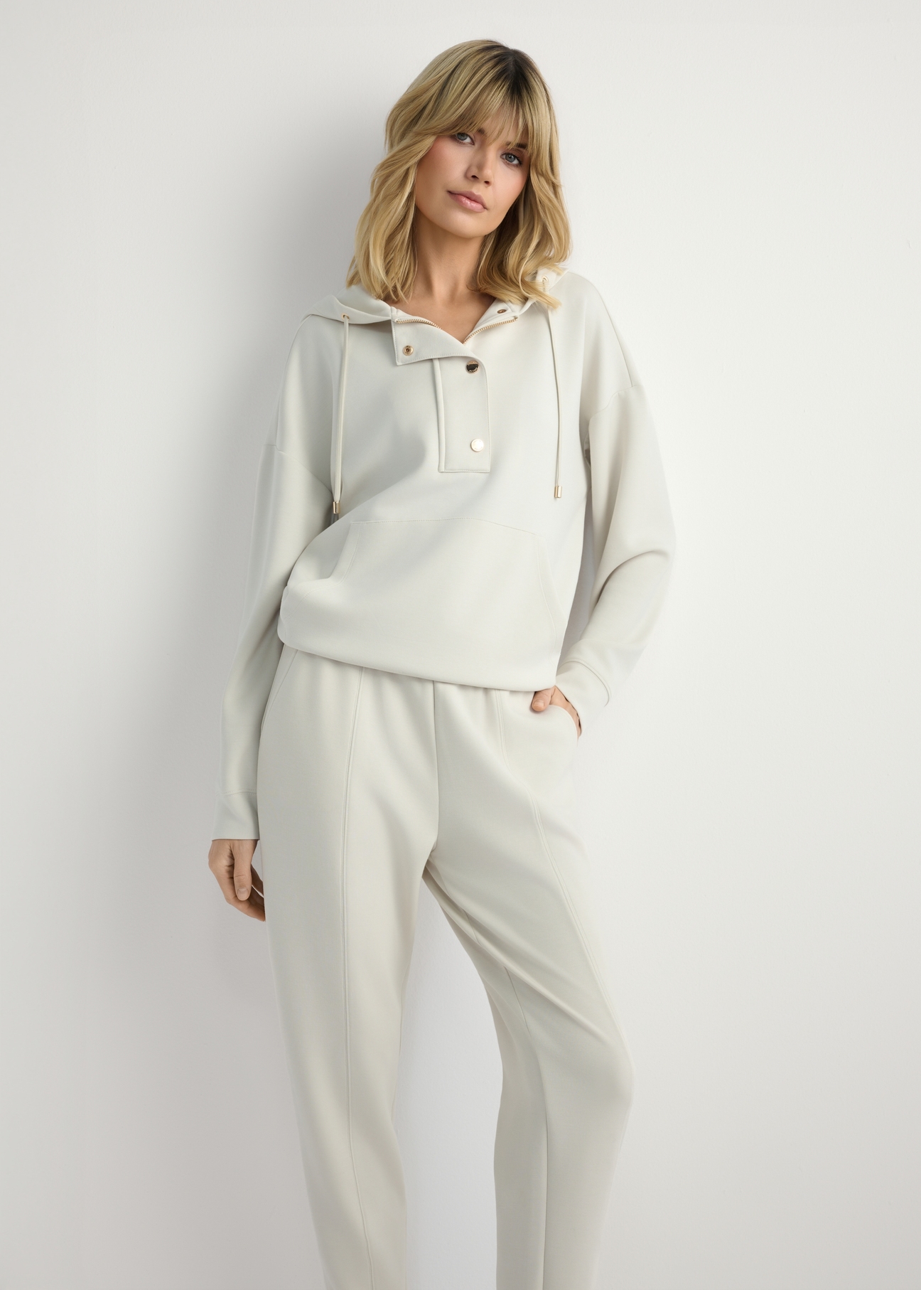 Svetlobéžová dámska mikina s kapucňou BLZDT-0111A-1A(W26), pohľad spredu na produkt na modelke. Viditeľná polovica siluety.