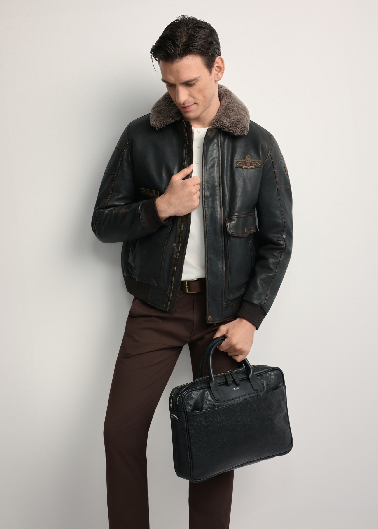 Čierna kožená pánska taška TORMS-0299A-99(Z25) - diagonálny pohľad na produkt, ktorý drží modelka, na bielom pozadí. Viditeľné celé telo.