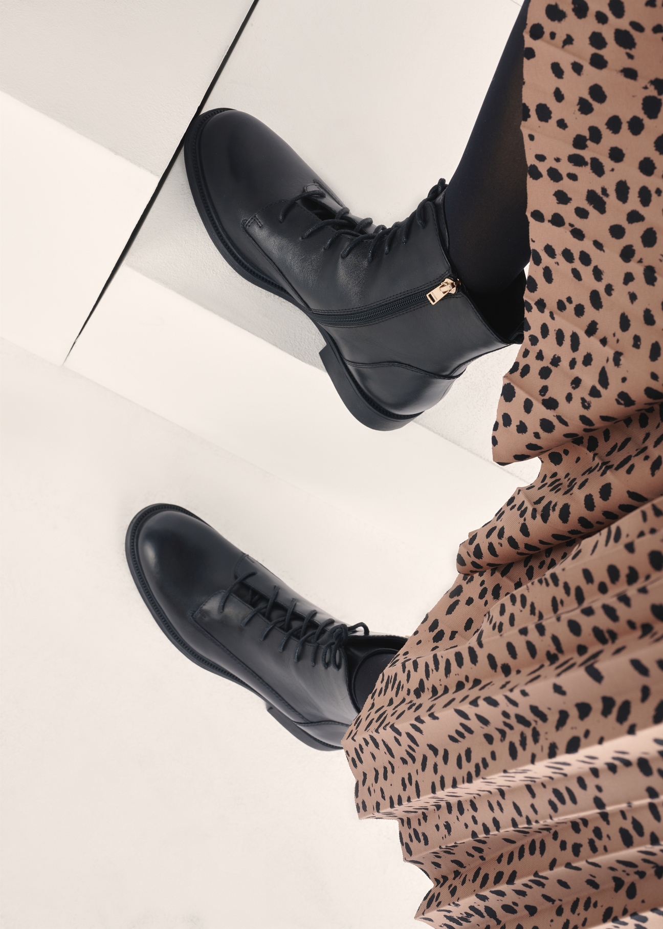 Čierne dámske kožené členkové čižmy BUTYD-1115-99(Z25), pohľad na produkt na nohách modelky na svetlom pozadí.