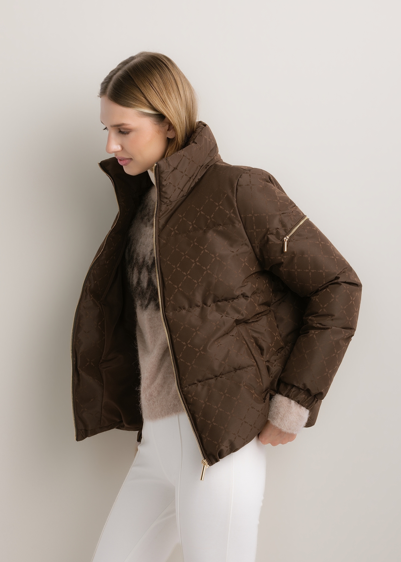 Dámska tmavohnedá monogramová bunda so stojačikom KURDT-0694-1I(Z26), diagonálny pohľad na produkt na modelke. Viditeľná polovica siluety.