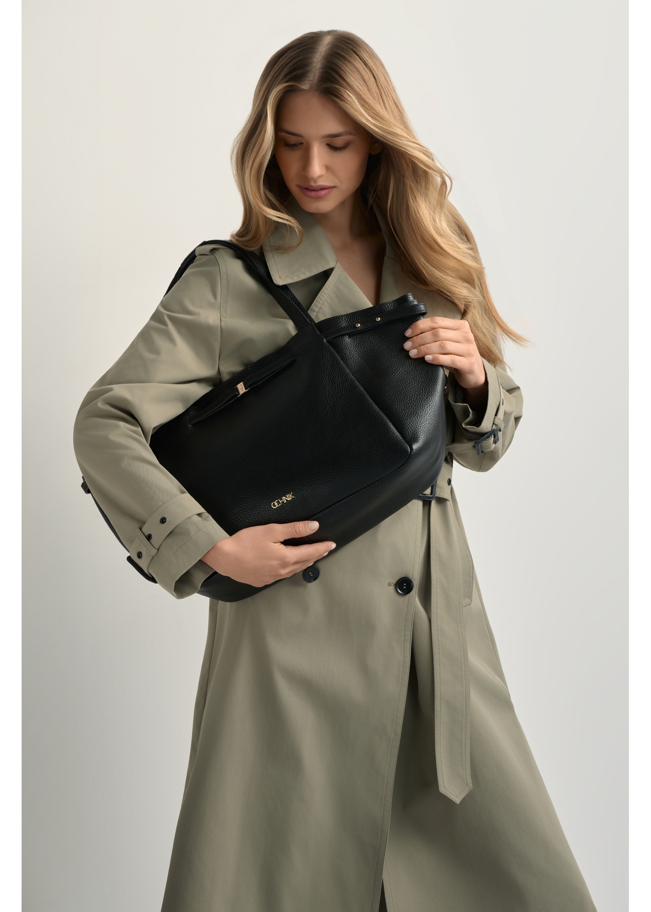 Čierna kožená nákupná kabelka TORES-1207-9I(W26) - pohľad spredu na produkt, na modelke, na svetlom pozadí. Viditeľná silueta po kolená.