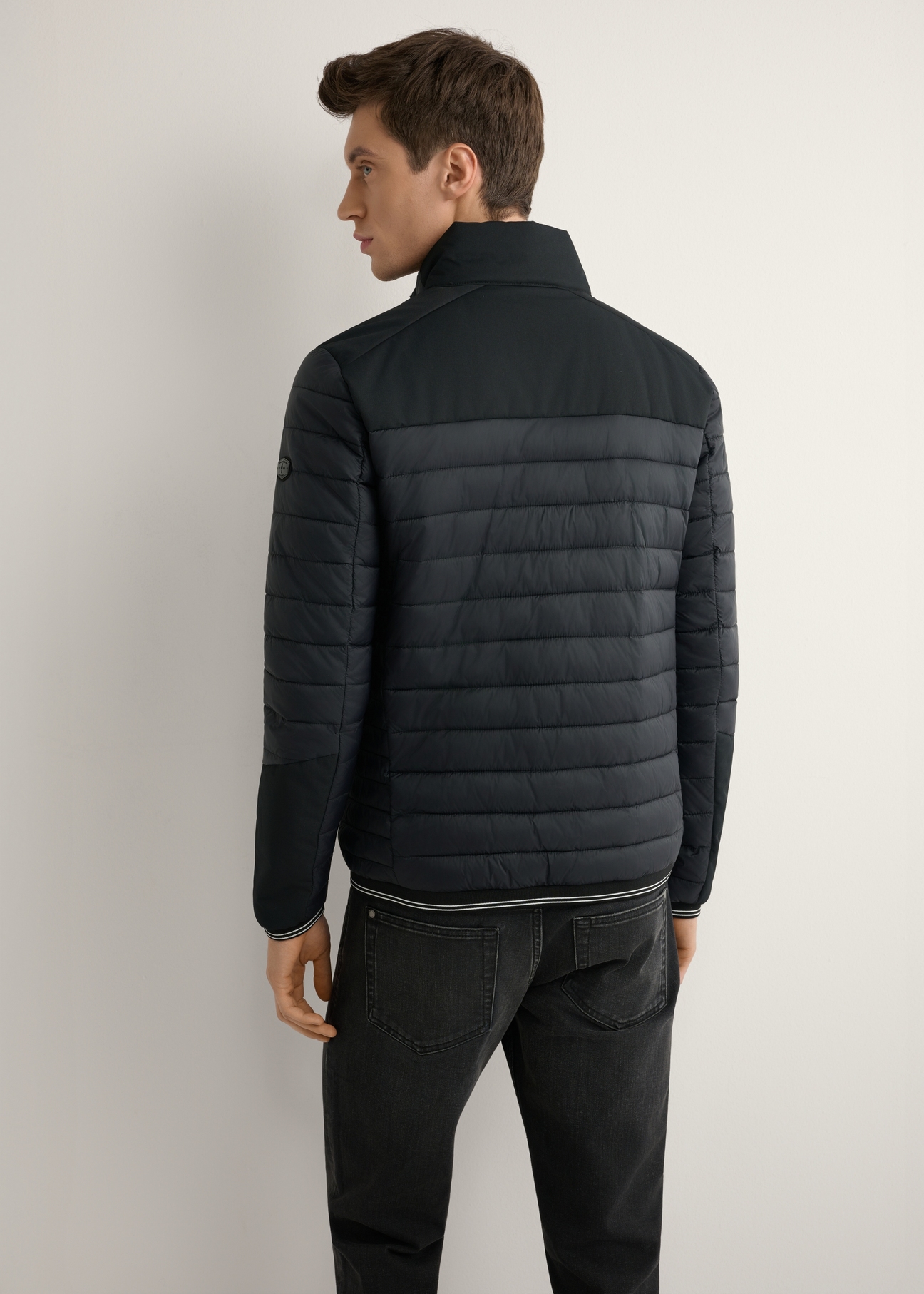 Pánska čierna prechodná bunda KURMT-0358A-99(W26) - pohľad na výrobok zozadu na modeli, na svetlom pozadí. Viditeľná polovica siluety.