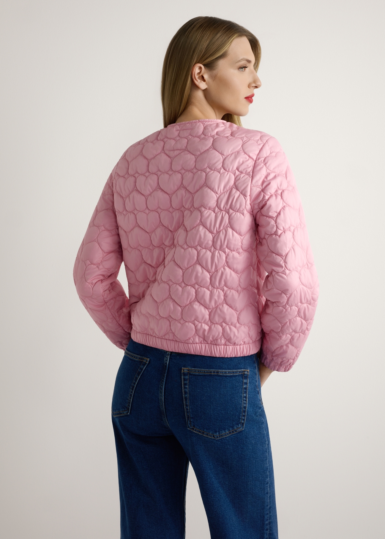 Ružová dámska prešívaná bunda KURDT-0630-5B(W26), pohľad na produkt zozadu na modelke, viditeľná polovica siluety.