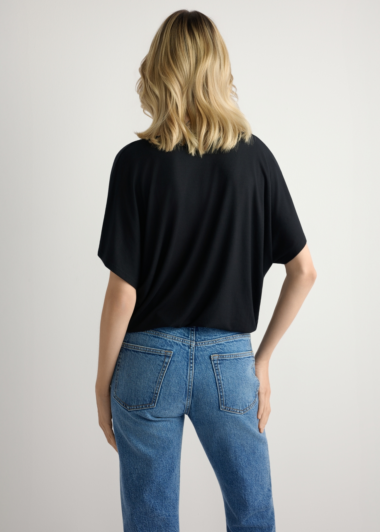 Čierna dámska blúzka BLUDT-0202-99(W26), pohľad na modelku zozadu. Viditeľná polovica siluety.