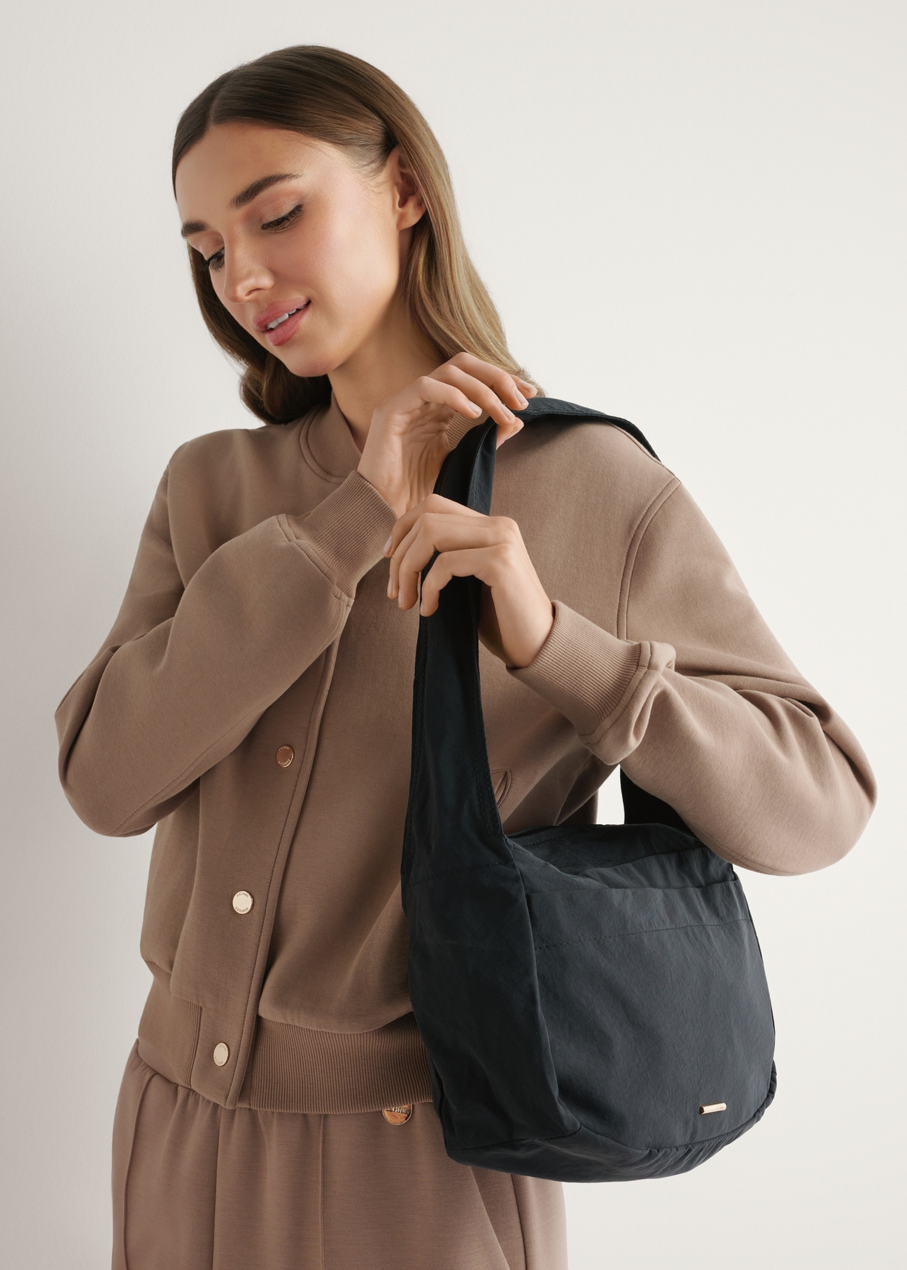 Čierna nylonová dámska kabelka TOREN-0338-99(W26), diagonálny pohľad na produkt na ramene modelky.