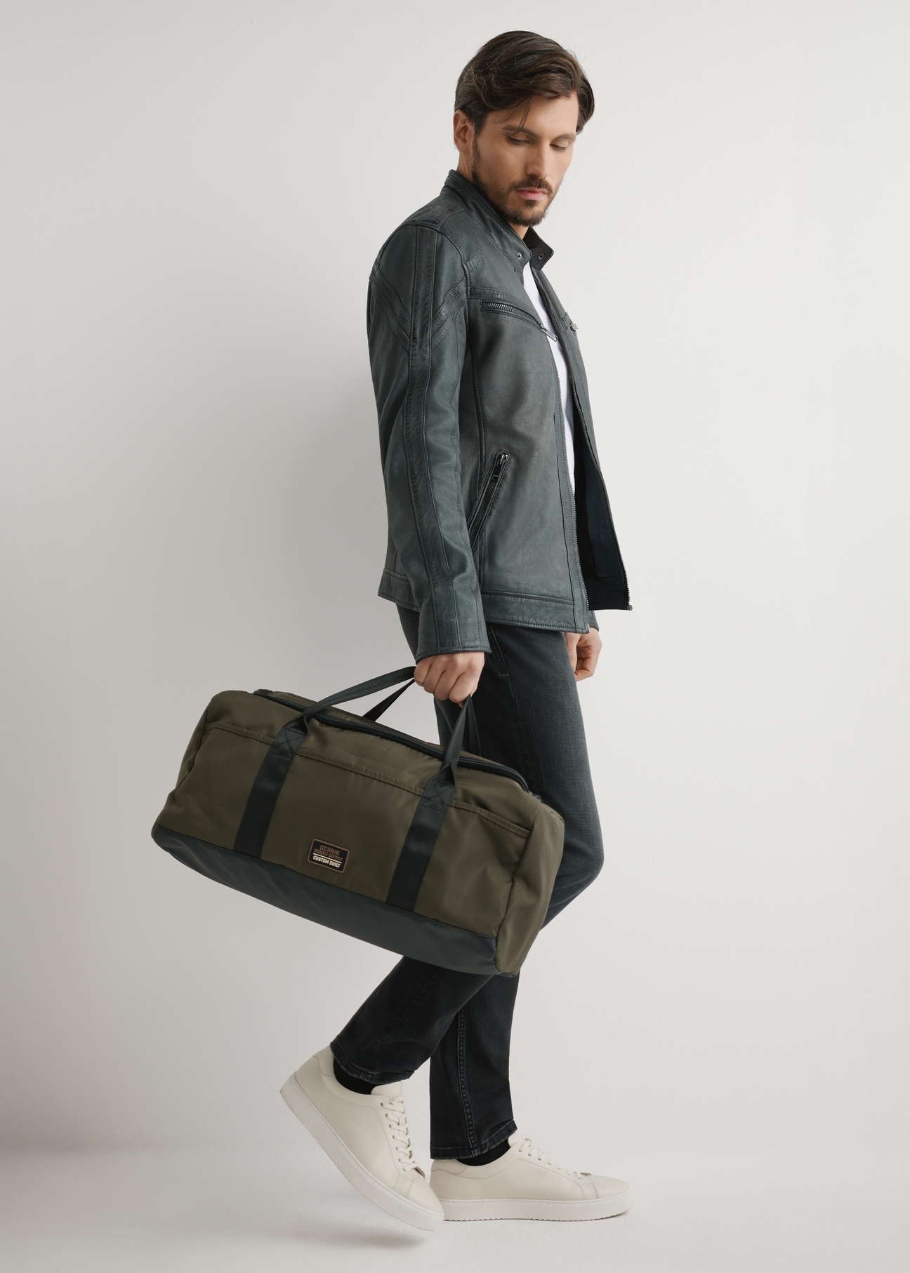 Kaki cestovná taška TORMN-0417-8D(W26) - pohľad spredu na produkt, ktorý drží modelka, na svetlom pozadí.