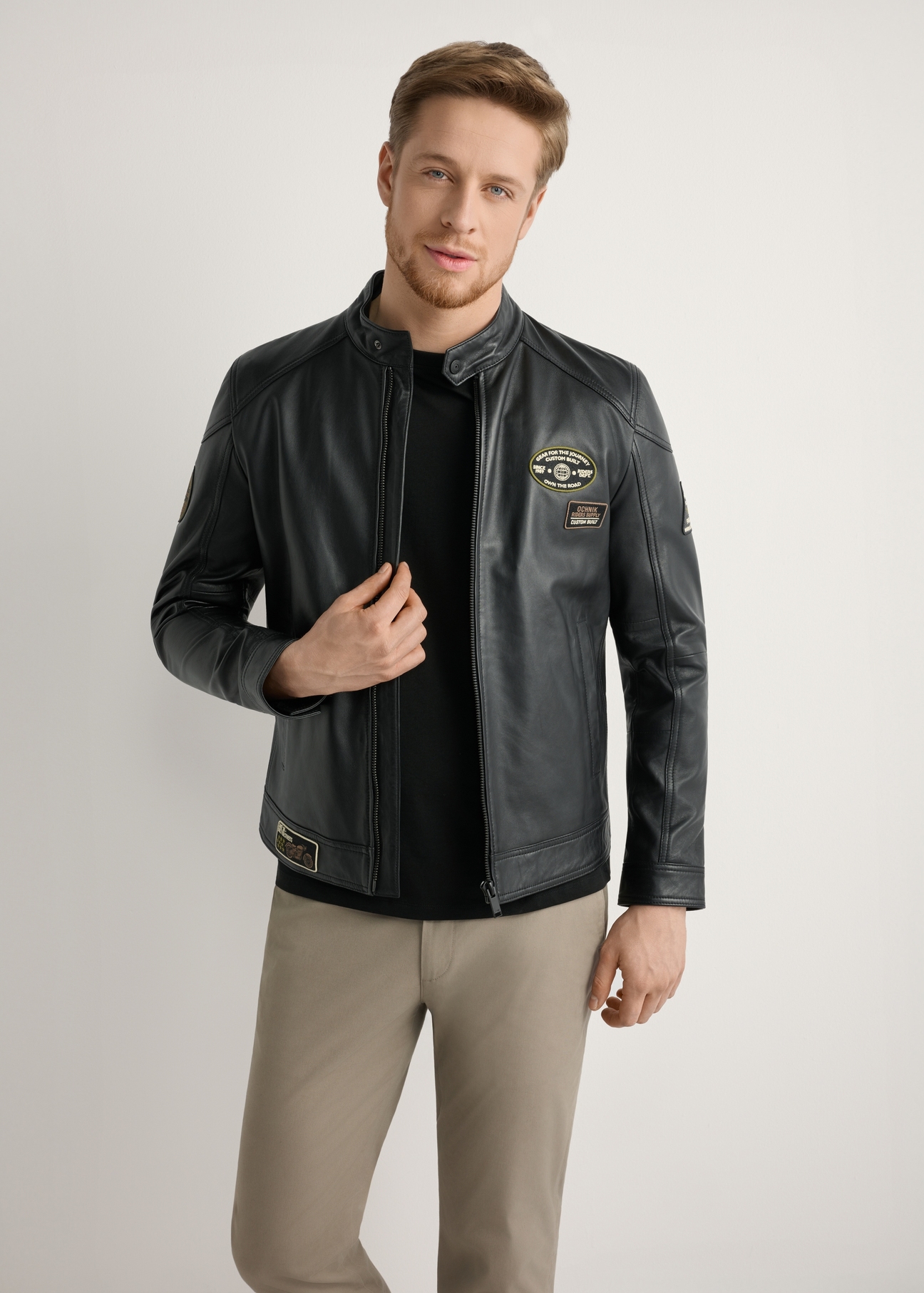 Pánska čierna kožená bunda KURMS-0301A-99(W26) - pohľad spredu na produkt, na modelke, na svetlom pozadí. Viditeľná polovica siluety.