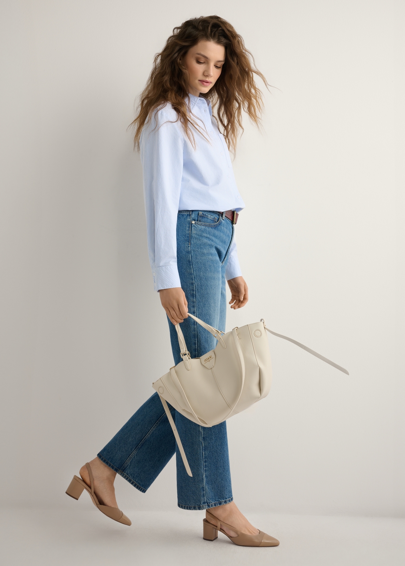 Dámska biela kabelka cez rameno TOREC-1231-0B(W26), pohľad na produkt v ruke modelky. Viditeľné celé telo.