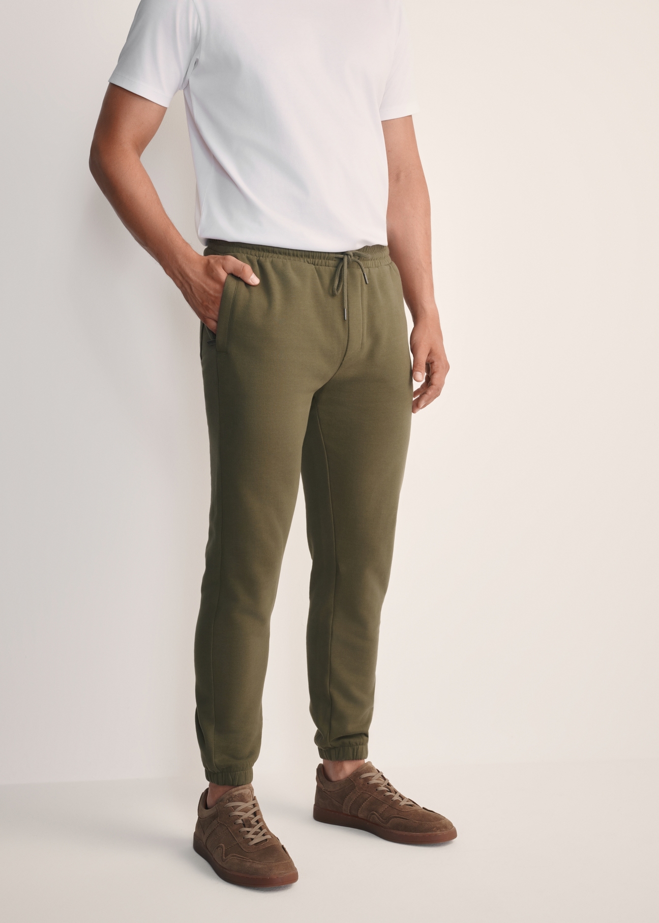 Pánske khaki tepláky SPOMT-0101-55(Z25), pohľad spredu na produkt na modelke. Viditeľná polovica siluety.