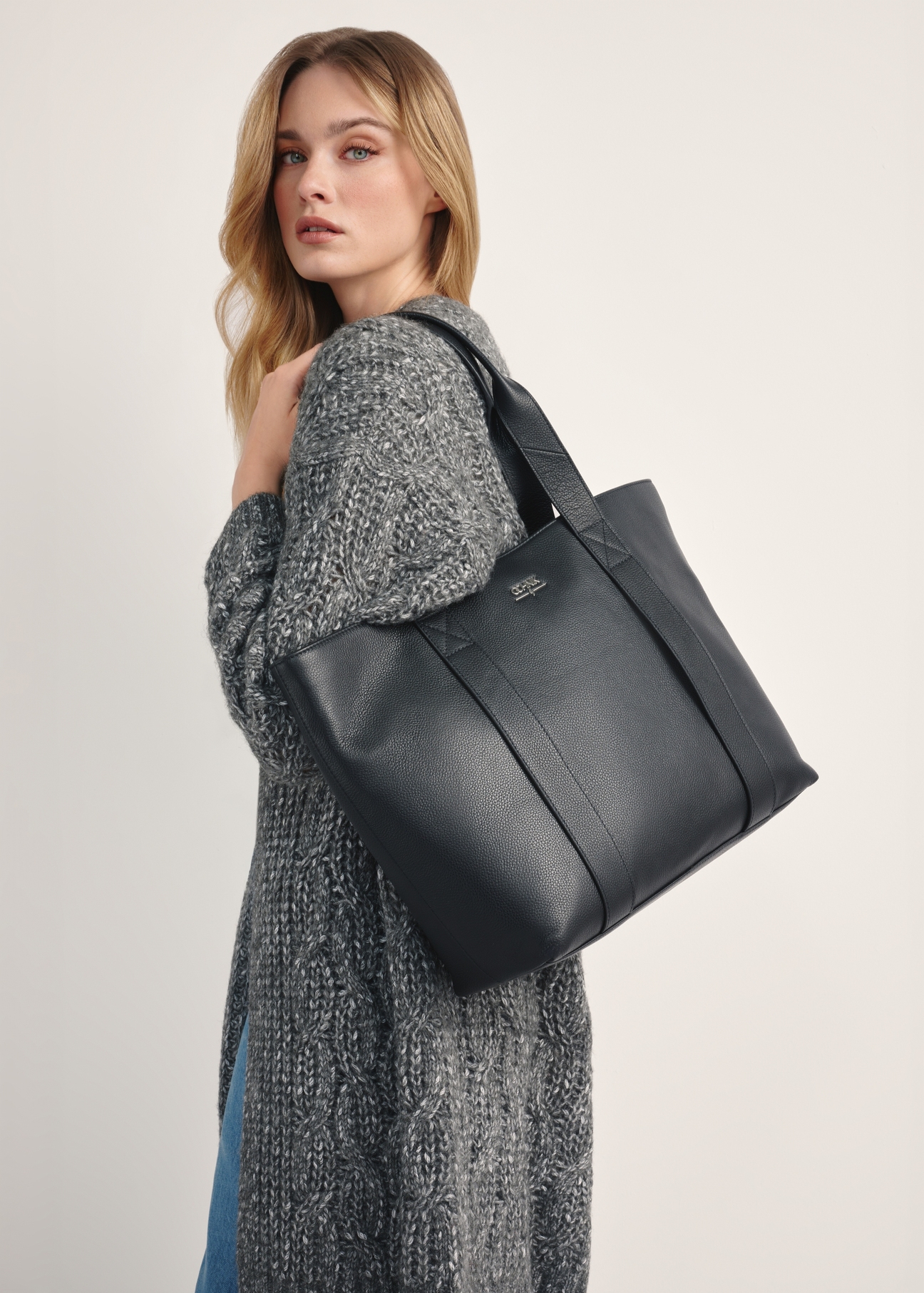 Čierna elegantná dámska nákupná taška TORES-1200-99(Z25), pohľad na produkt na ramene modelky na svetlom pozadí.