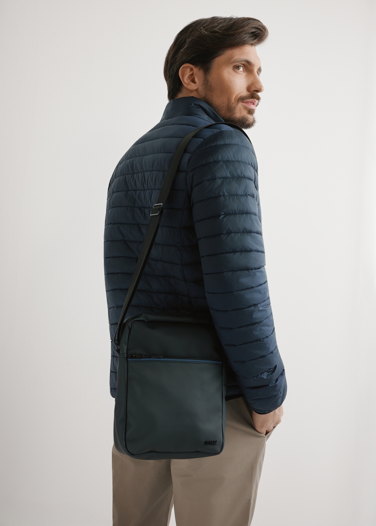 Pánska čierna crossbody kabelka TORMN-0395-9J(W26) - pohľad na produkt spredu, na modelke, na svetlom pozadí. Viditeľná silueta po pás.