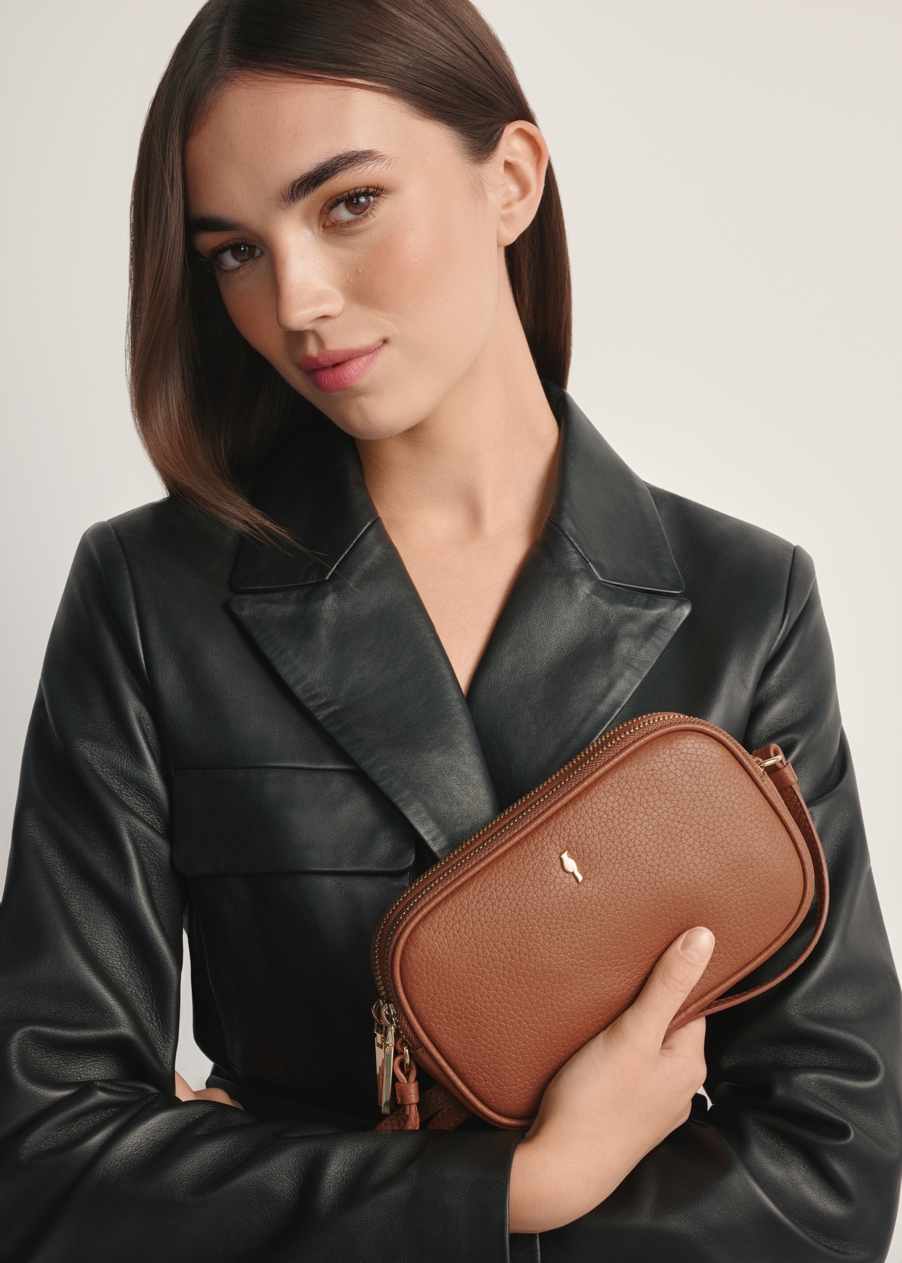 Malá kožená dámska kabelka v ťavej farbe TORES-0466E-1D(W26), pohľad na produkt spredu na modelke, viditeľná polovica siluety.