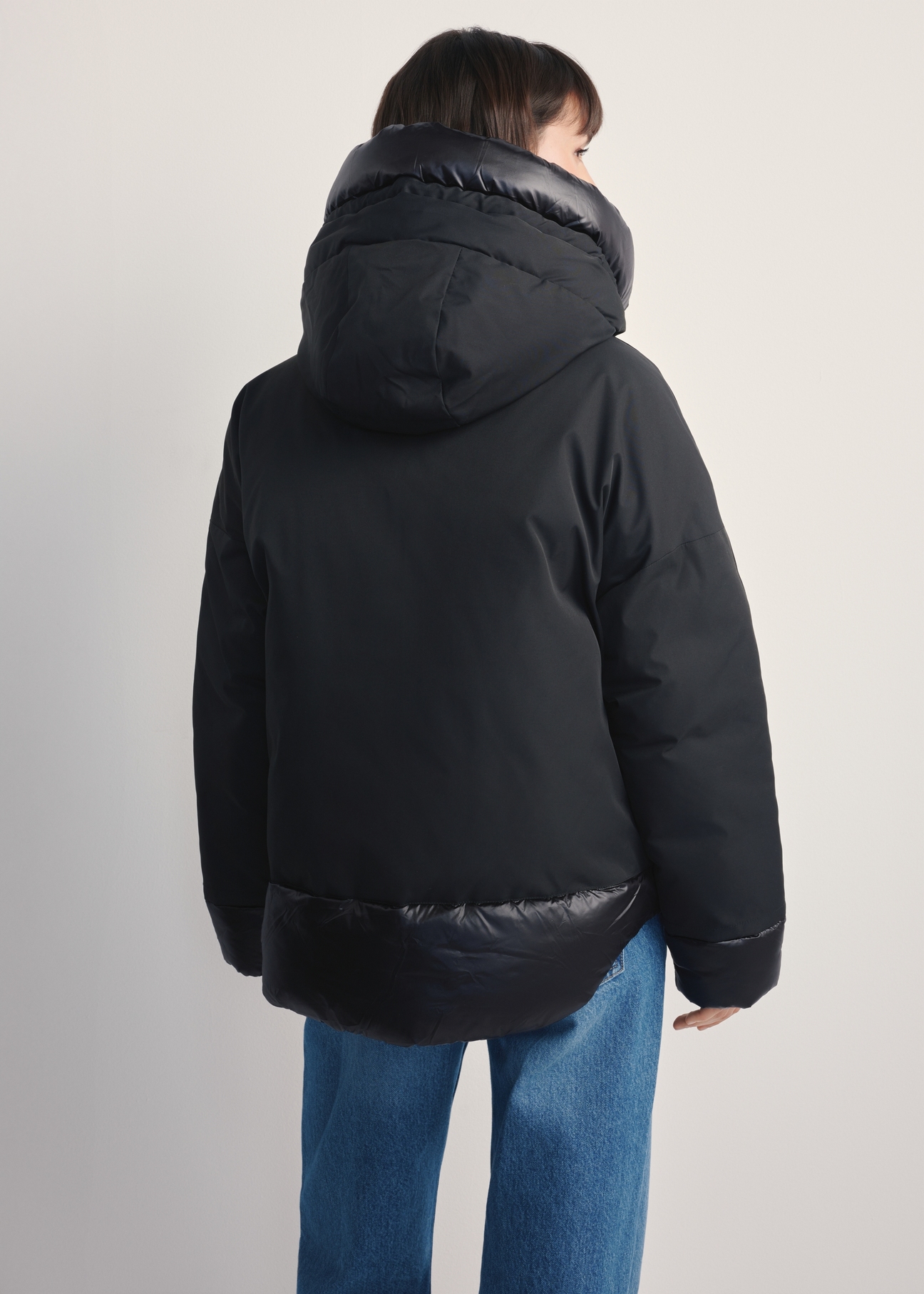 Čierna oversized dámska bunda KURDT-0605-99(Z25), pohľad na modelku zozadu. Viditeľná polovica siluety.