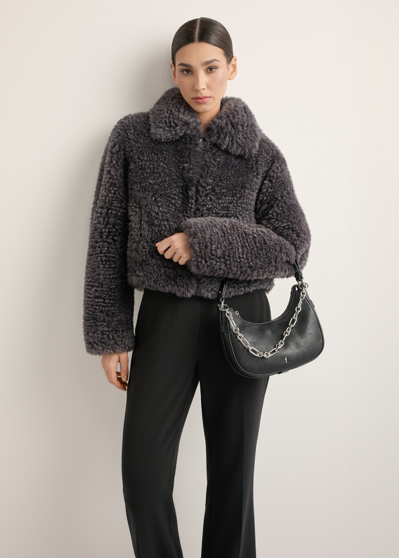Čierna dámska kabelka hobo s ozdobnými šperkami TOREC-1326-99(Z26), diagonálny pohľad na produkt na modelke. Viditeľná polovica siluety.
