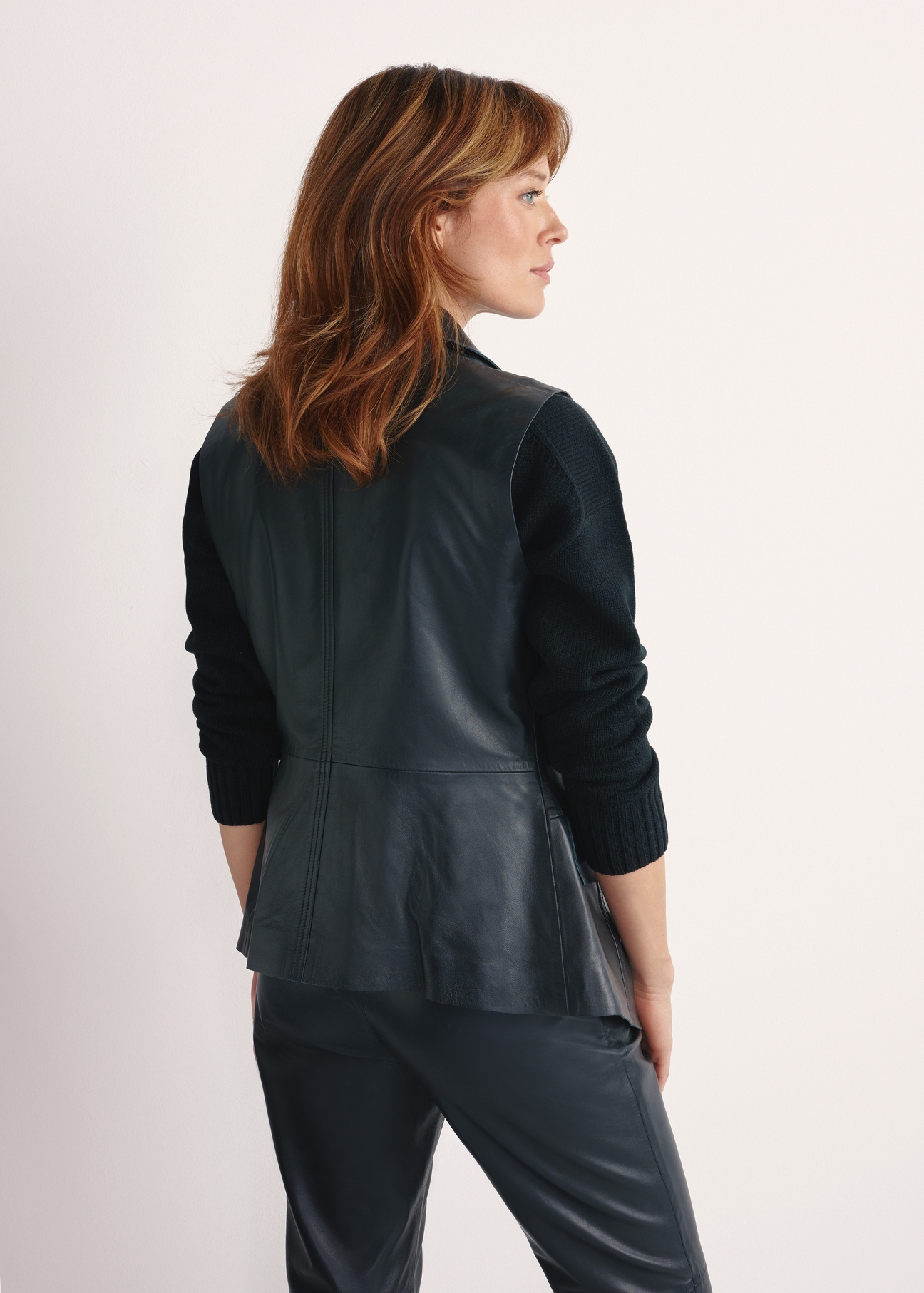 Dámska čierna kožená vesta KAMDS-0010-5344(W25), pohľad na produkt zozadu na modelke, viditeľná polovica siluety.