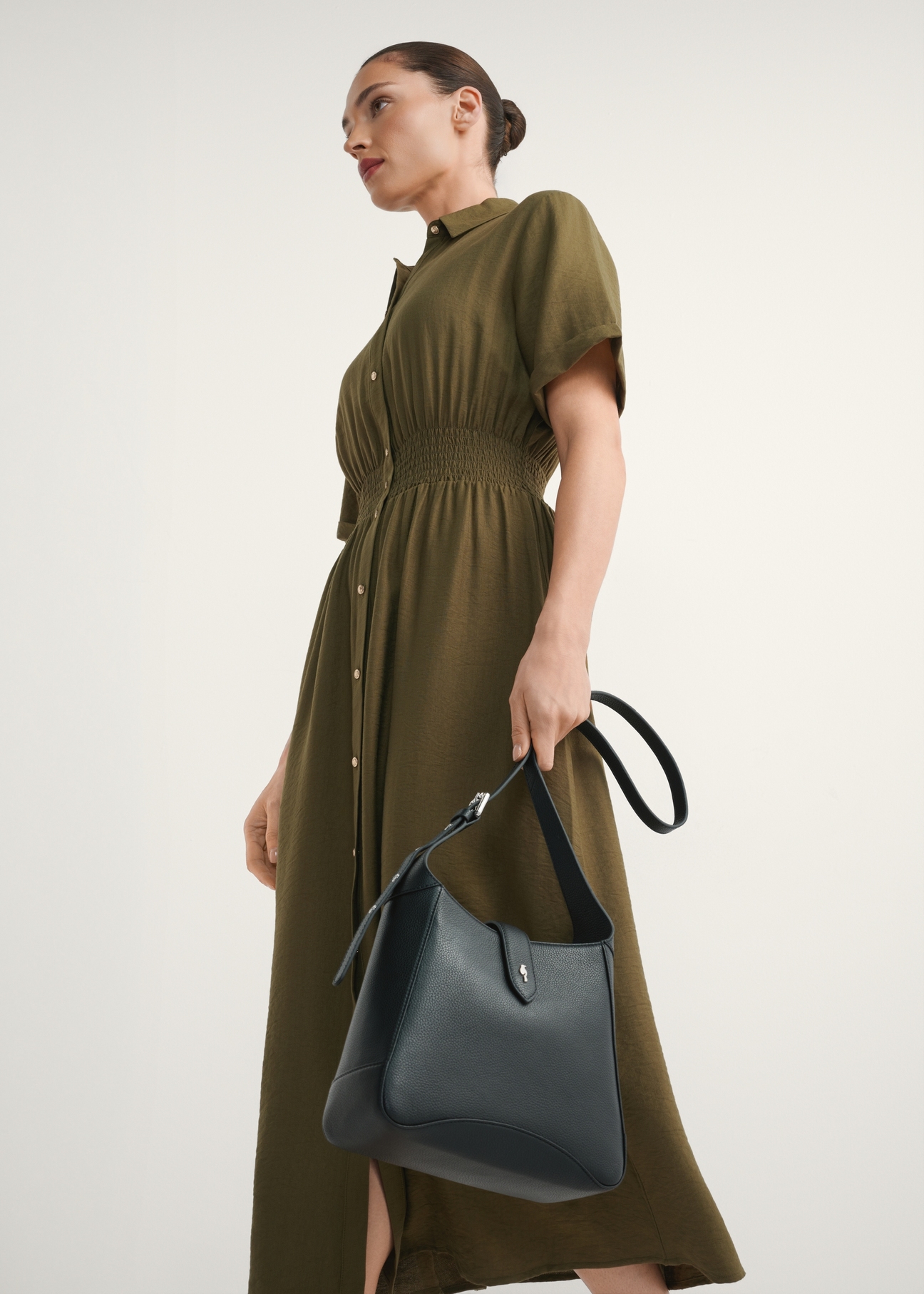 Čierna kožená kabelka cez rameno TORES-1211-9I(W26) - mierne diagonálny pohľad na produkt, ktorý drží modelka, na svetlom pozadí. Viditeľná silueta po kolená.