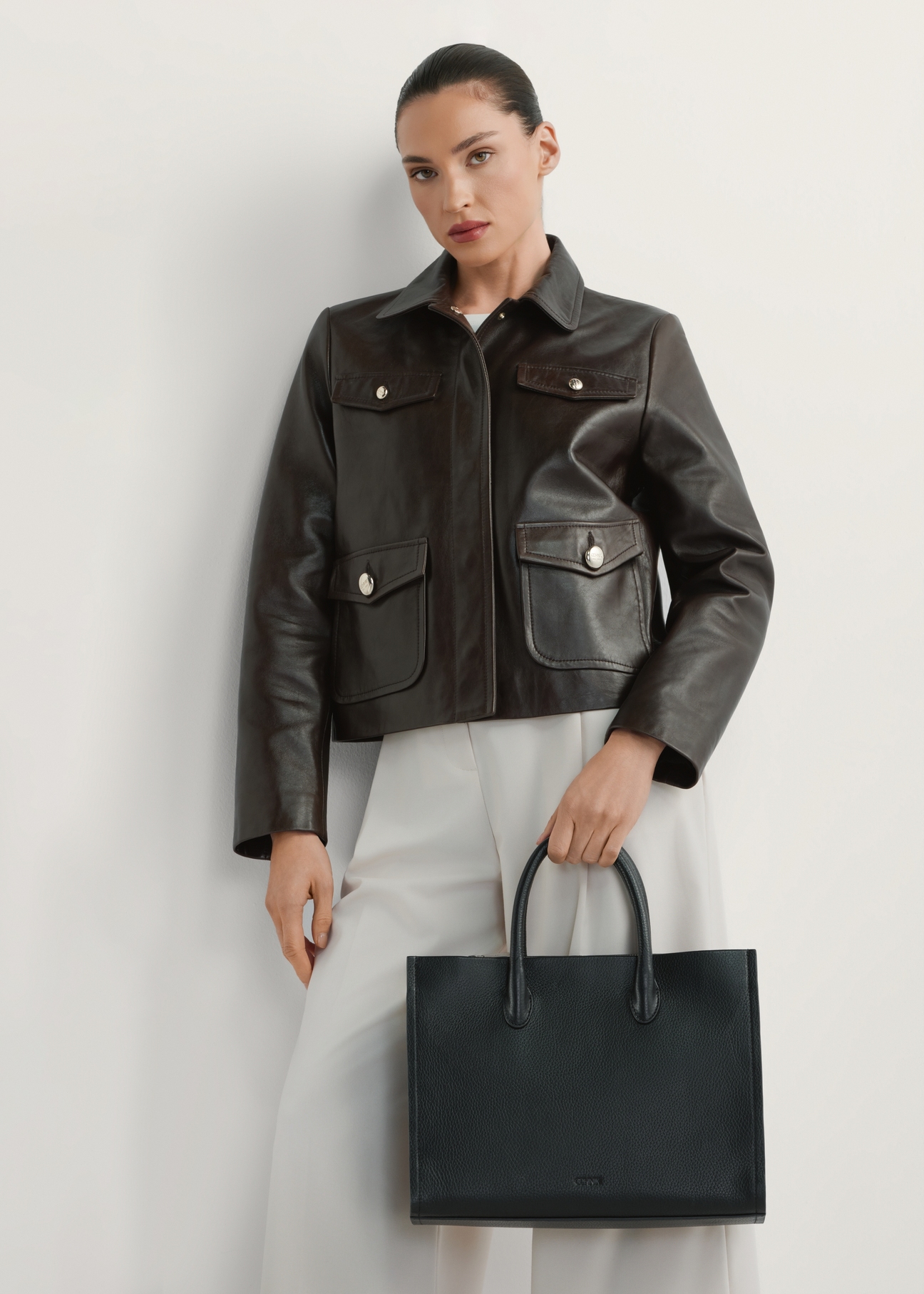 Dámska čierna kožená kabelka TORES-1206-9I(W26), pohľad na produkt v ruke modelky. Viditeľná polovica siluety.