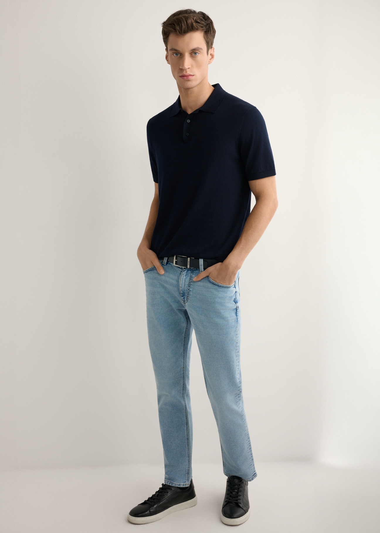 Pánske modré rifle JEAMT-0021-7B(W26), pohľad spredu na produkt na modelke. Viditeľná celá silueta.