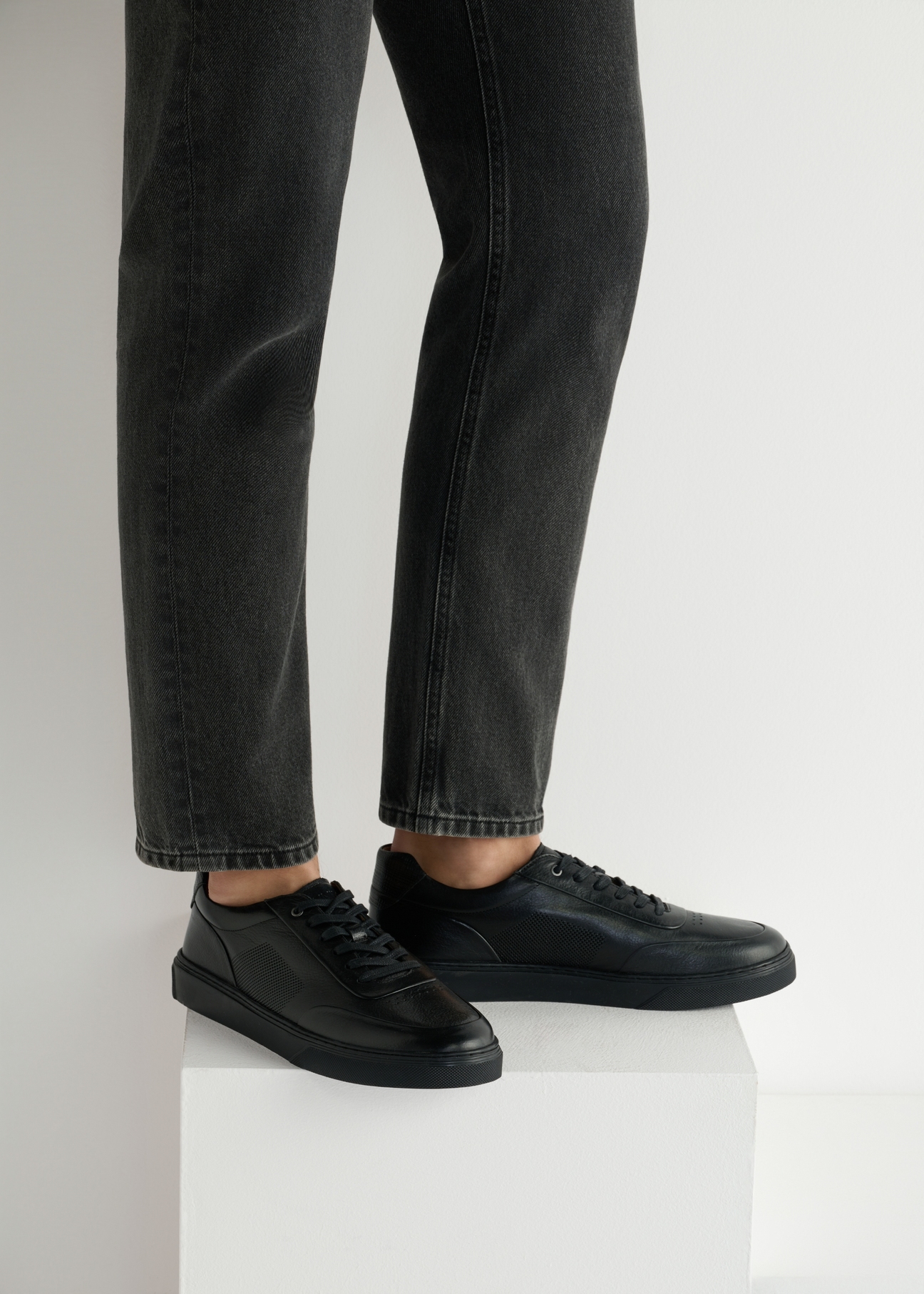 Čierne kožené pánske športové topánky BUTYM-0484-99(W25), bočný pohľad na produkt na modeli, viditeľná polovica siluety.