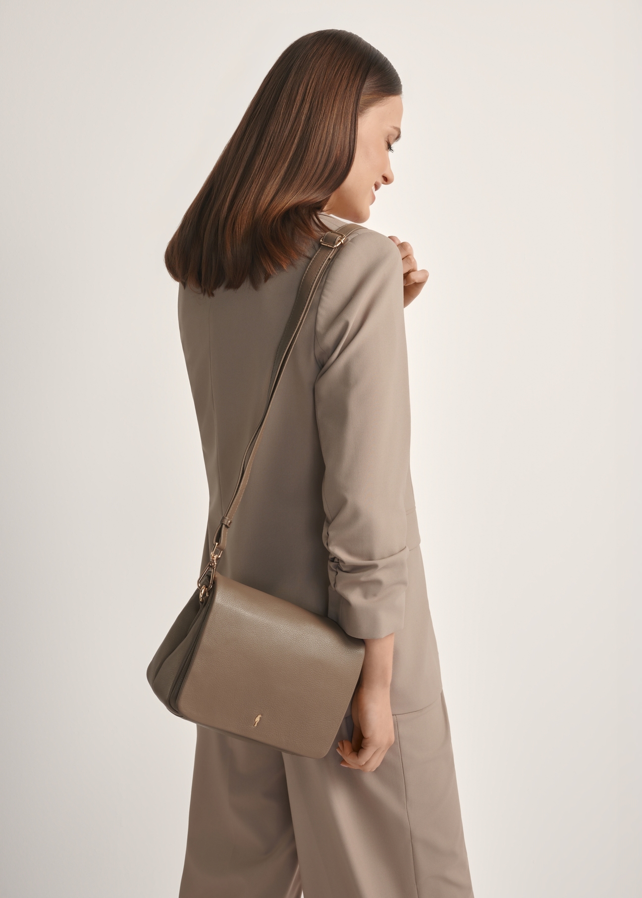 Dámska kožená kabelka tmavohnedej farby TORES-0911 F-1K(W26), pohľad spredu na produkt na modelke, viditeľná polovica siluety.