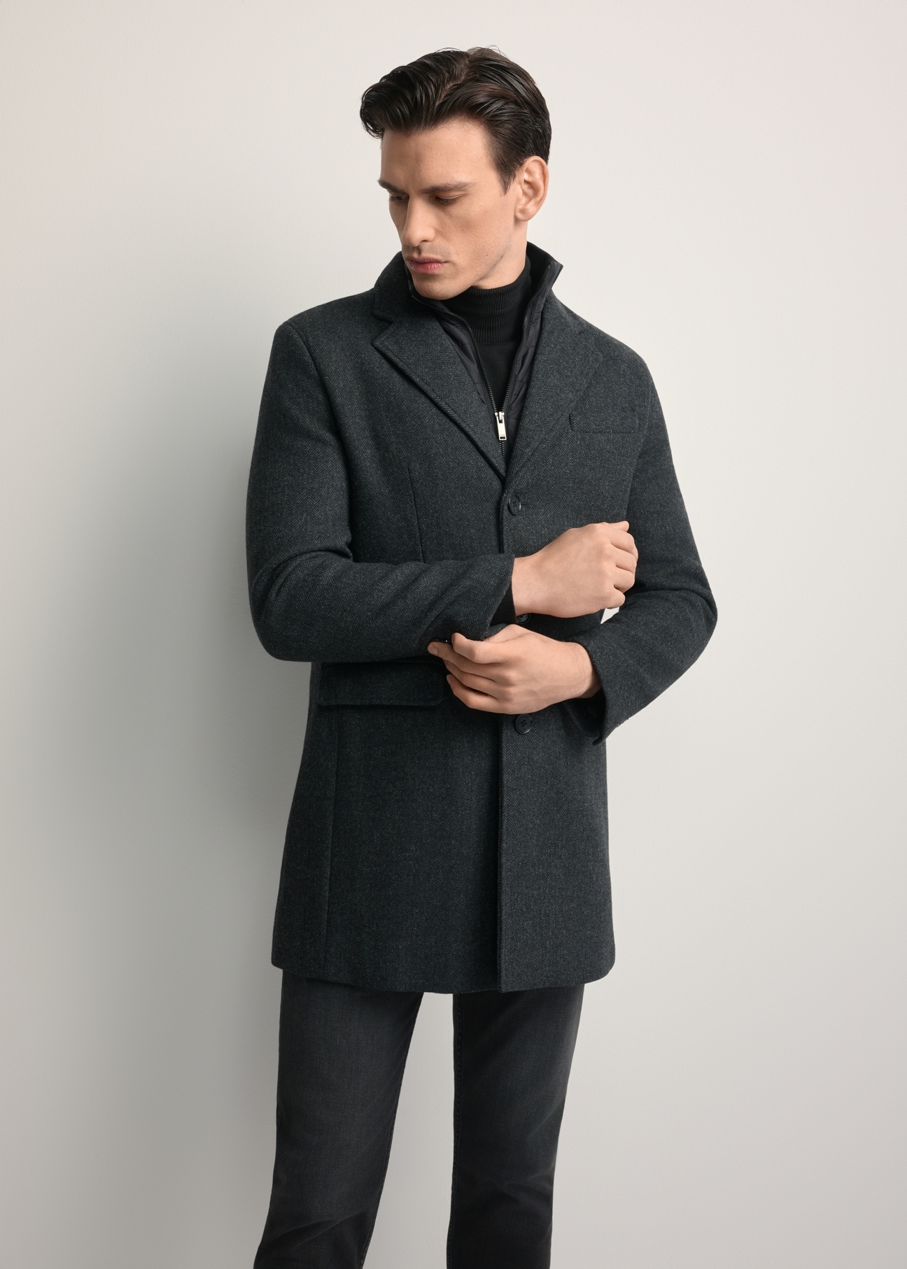 Pánsky vlnený kabát sivej farby PLAMT-0008-91(Z25), pohľad spredu na výrobok na modelke. Viditeľná polovica siluety.