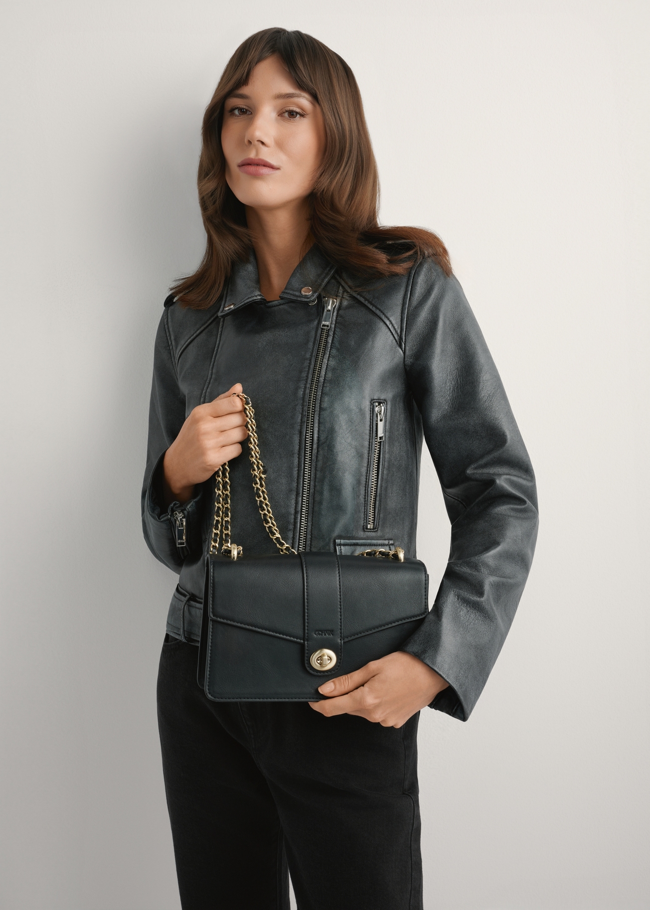 Čierna dámska taška cez rameno TOREC-1137-99(W26), pohľad na produkt v rukách modelky. Viditeľná polovica siluety.