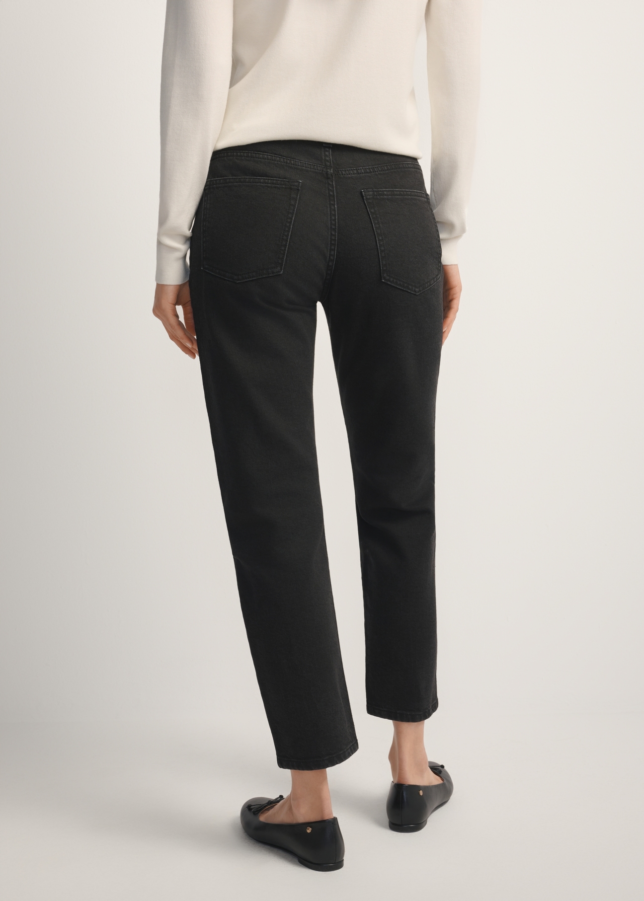 Dámske čierne džínsy JEADT-0011-99(W26), pohľad na modelku zozadu. Viditeľná polovica siluety.