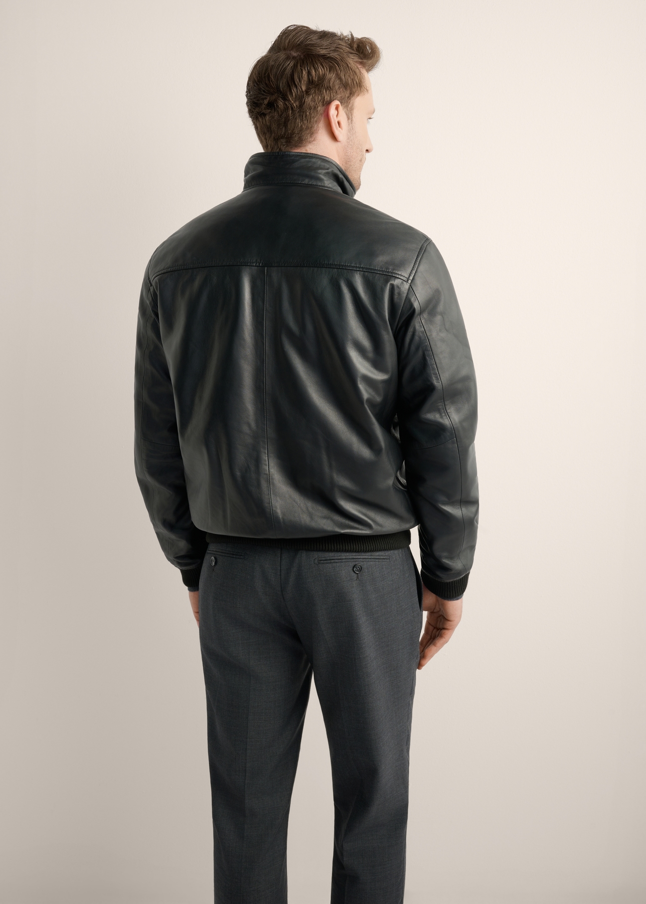 Pánska čierna kožená bomber bunda KURMS-0418-99(Z26), pohľad na produkt zozadu na modeli. Viditeľná polovica siluety.