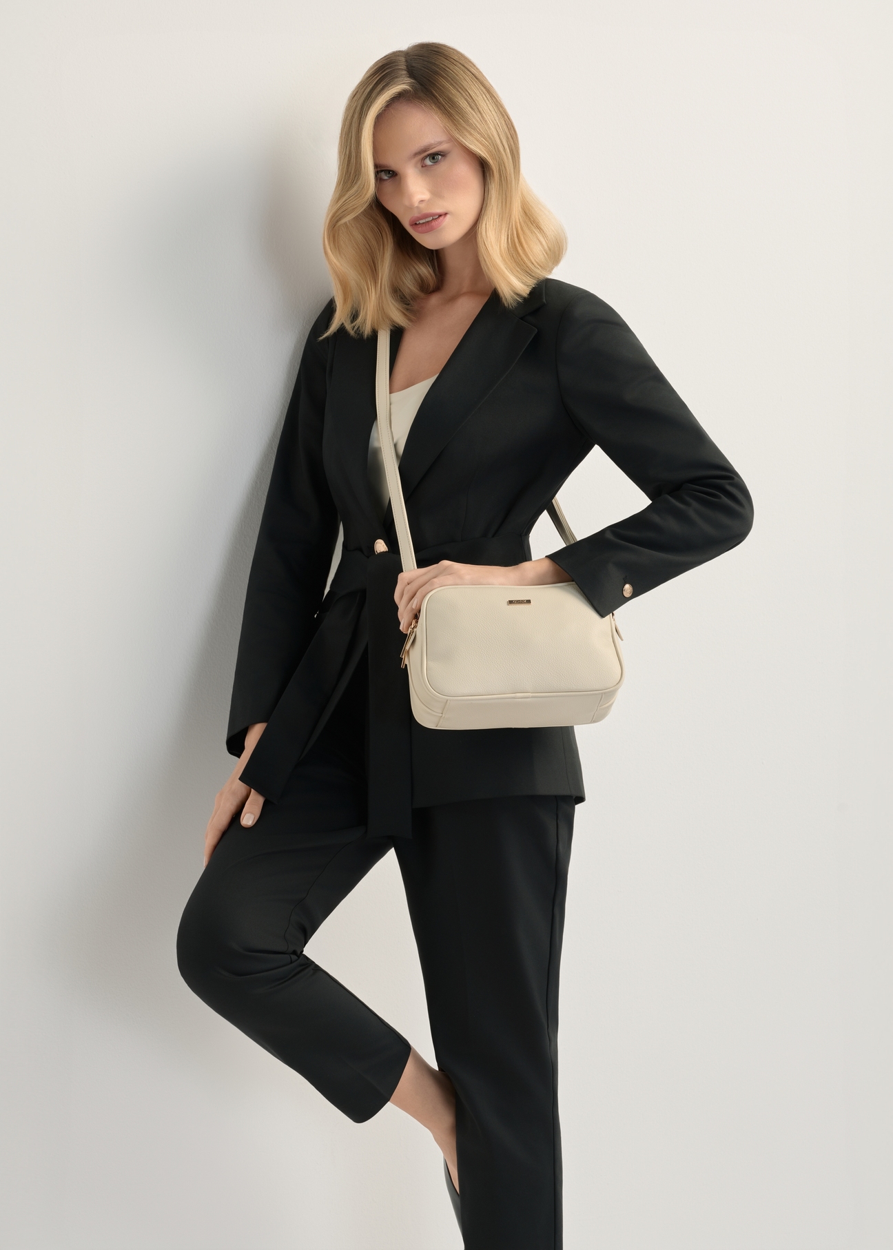 Dámska kabelka strednej veľkosti krémovej farby TOREC-1121-0B(W26), pohľad na produkt na ramene modelky. Viditeľná polovica siluety.