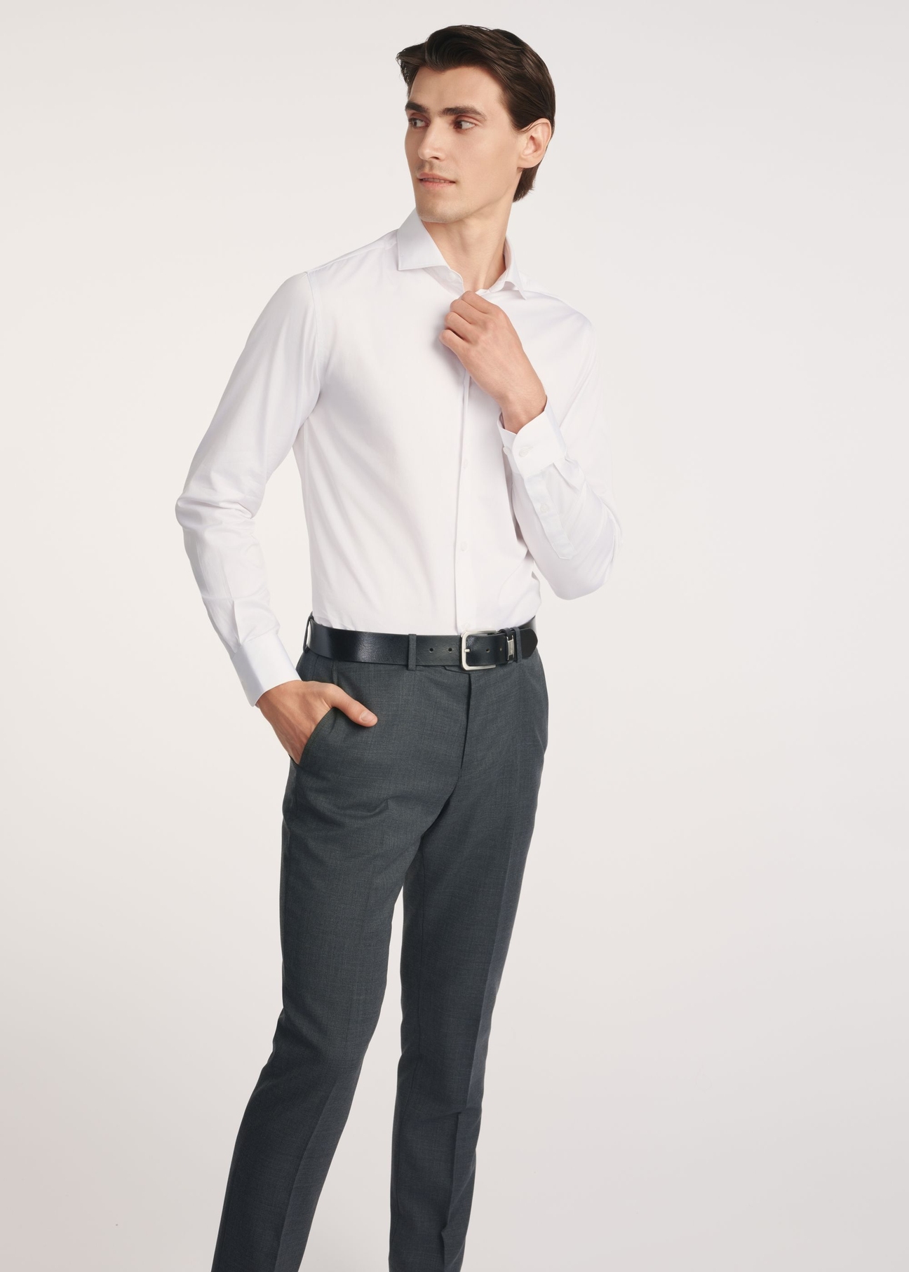 Pánska biela slim fit košeľa KOSMT-0352-0A(W26) - pohľad spredu na produkt, na modelke, na svetlom pozadí. Viditeľné celé telo.