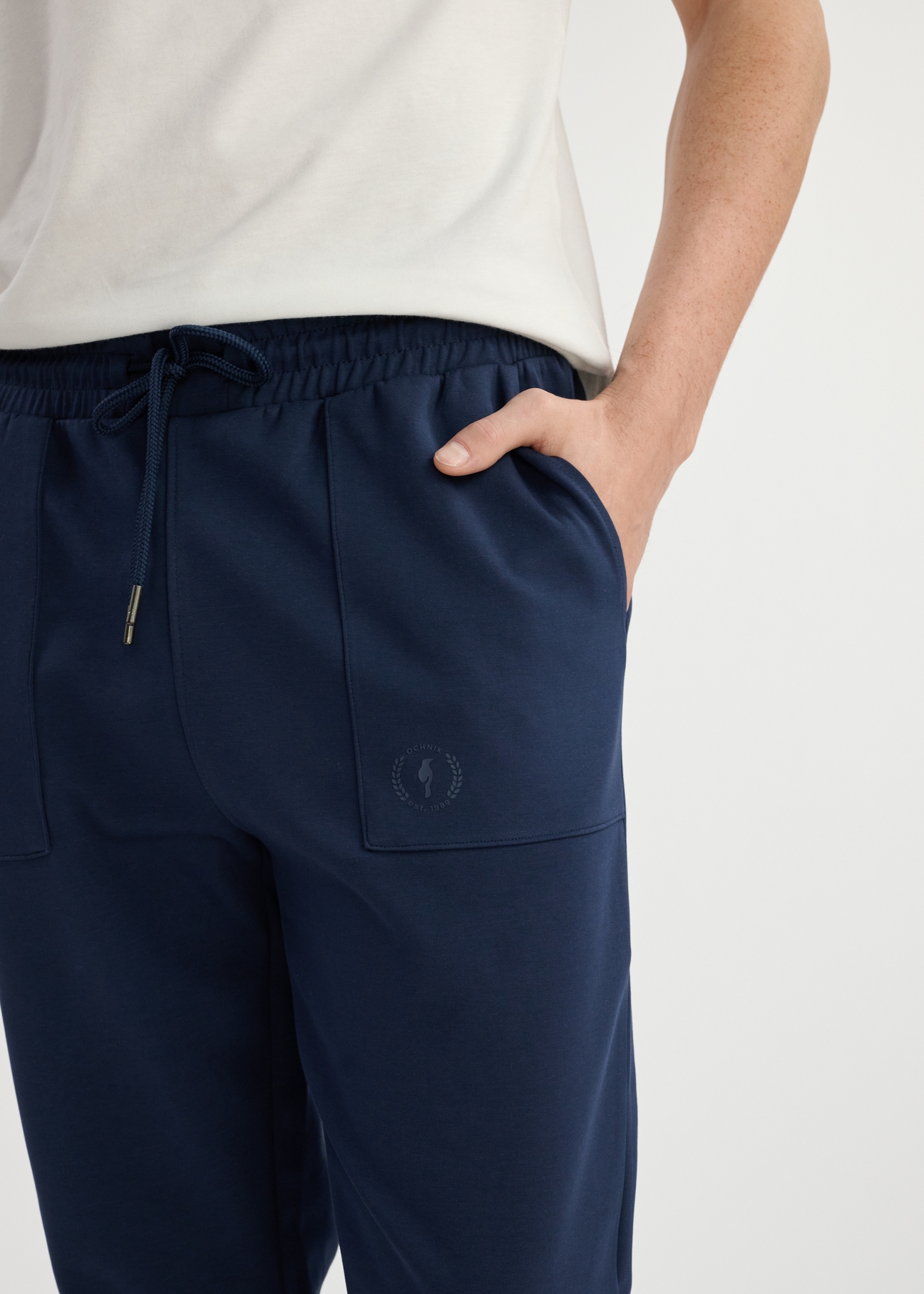 Pánske tmavomodré tepláky SPOMT-0109-69(W25) - detailný záber na predný detail modelu na bielom pozadí.