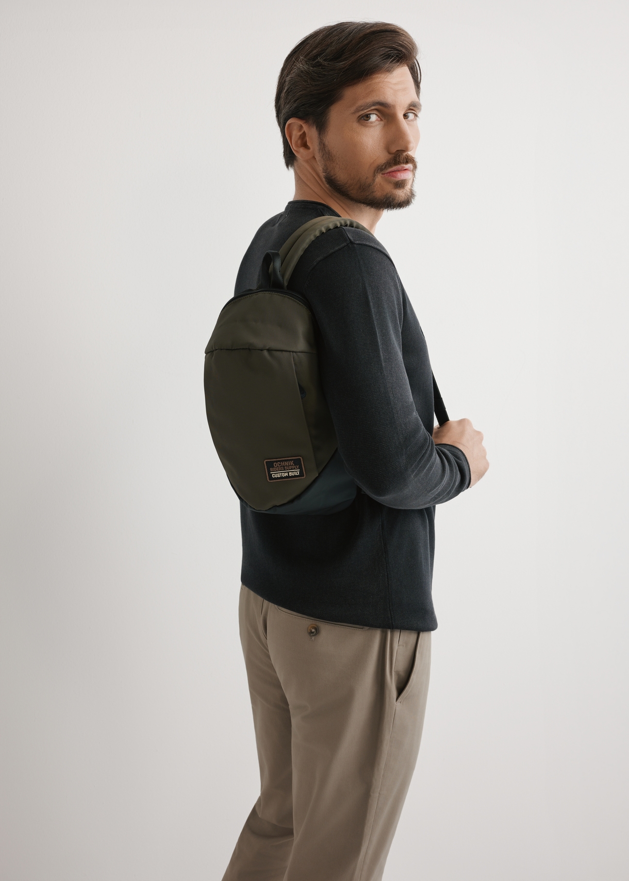 Pánska khaki kabelka cez rameno TORMN-0416-8D(W26) - pohľad na produkt mierne diagonálny, na svetlom pozadí. Viditeľná silueta po kolená.