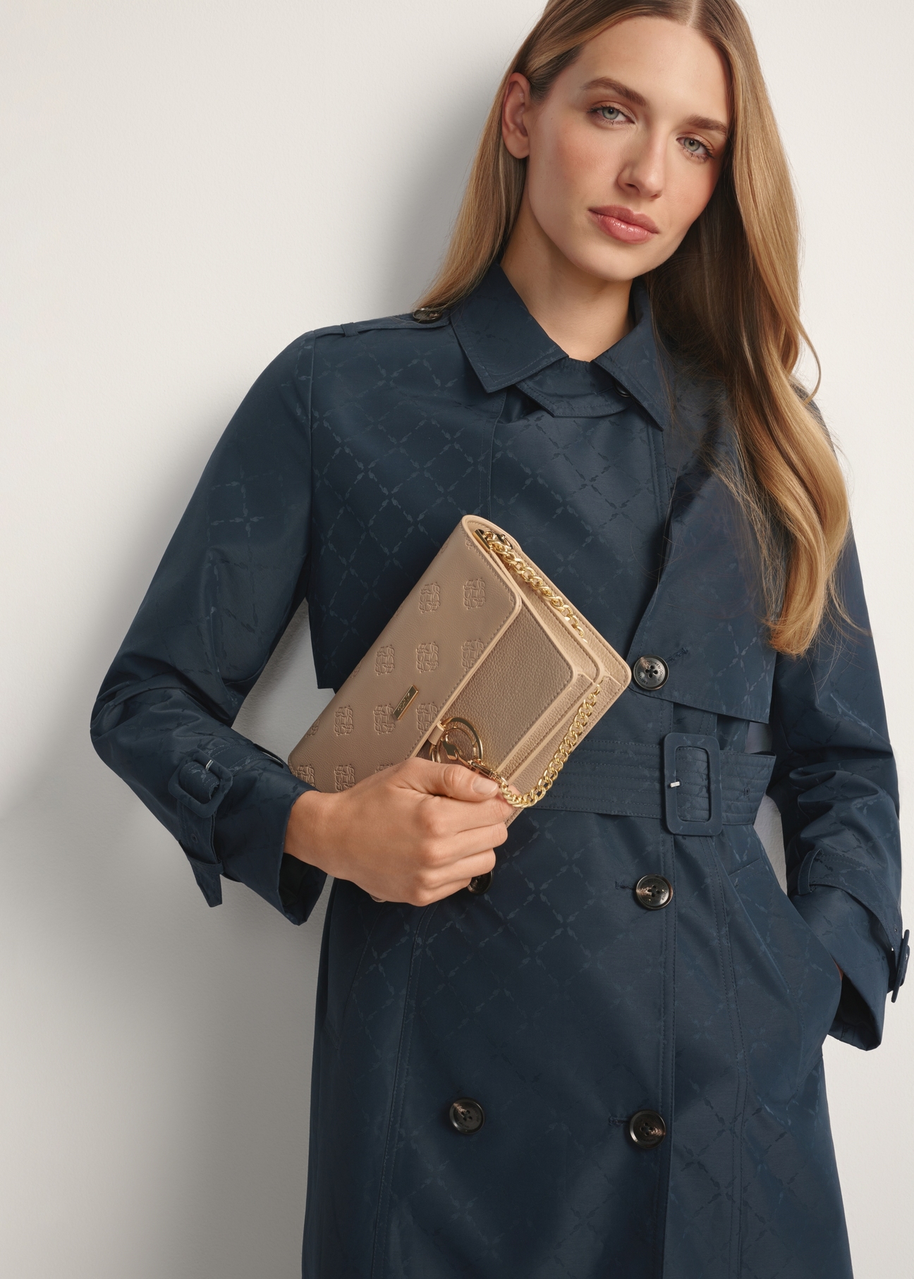 Béžová dámska kabelka s monogramom TOREC-0536-1P(W26), pohľad na produkt v ruke modelky. Viditeľná polovica siluety.