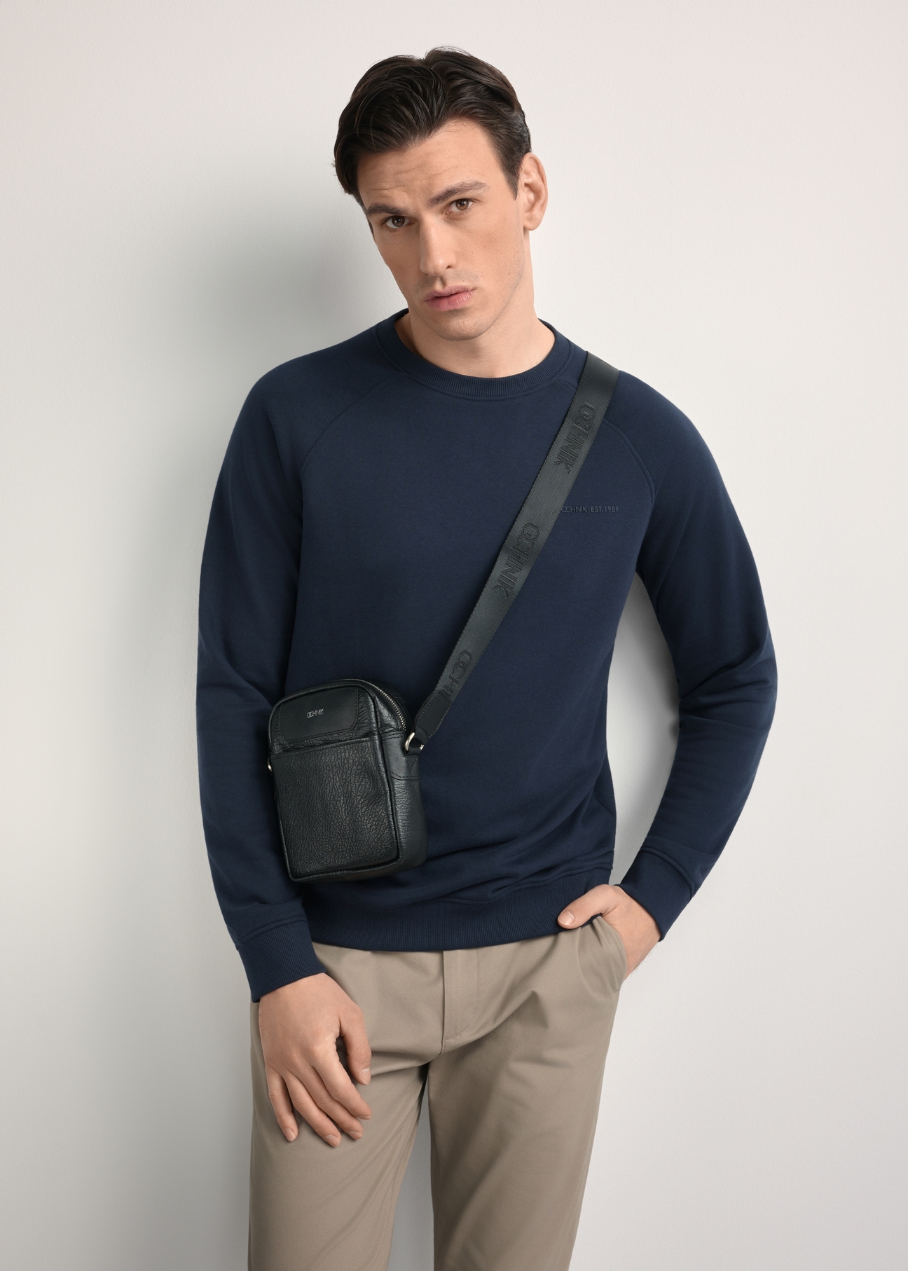 Pánska čierna kožená ľadvinka s logom TORMS-0296A-99(Z25) - diagonálny pohľad na produkt, modelovaný na bielom pozadí. Viditeľná silueta po kolená.