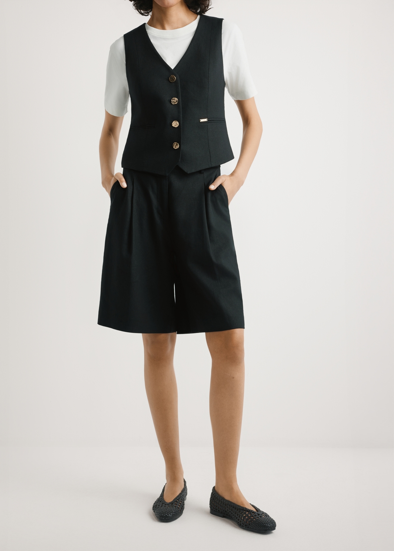 Dámske elegantné čierne šortky SZODT-0017-99(W26), pohľad spredu na produkt na modelke. Viditeľná polovica siluety.