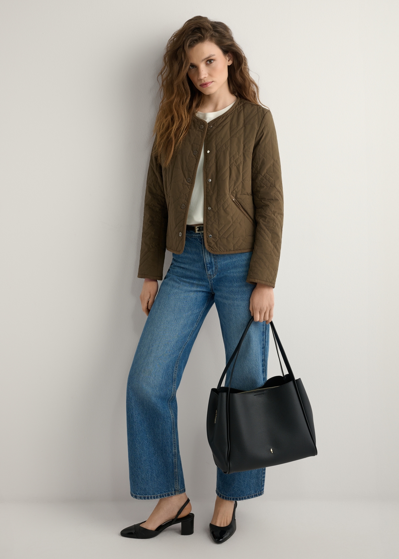 Čierna dámska nákupná taška TOREC-1183-99(W26) - mierne diagonálny pohľad na produkt, ktorý drží modelka, na svetlom pozadí. Viditeľná je celá silueta.