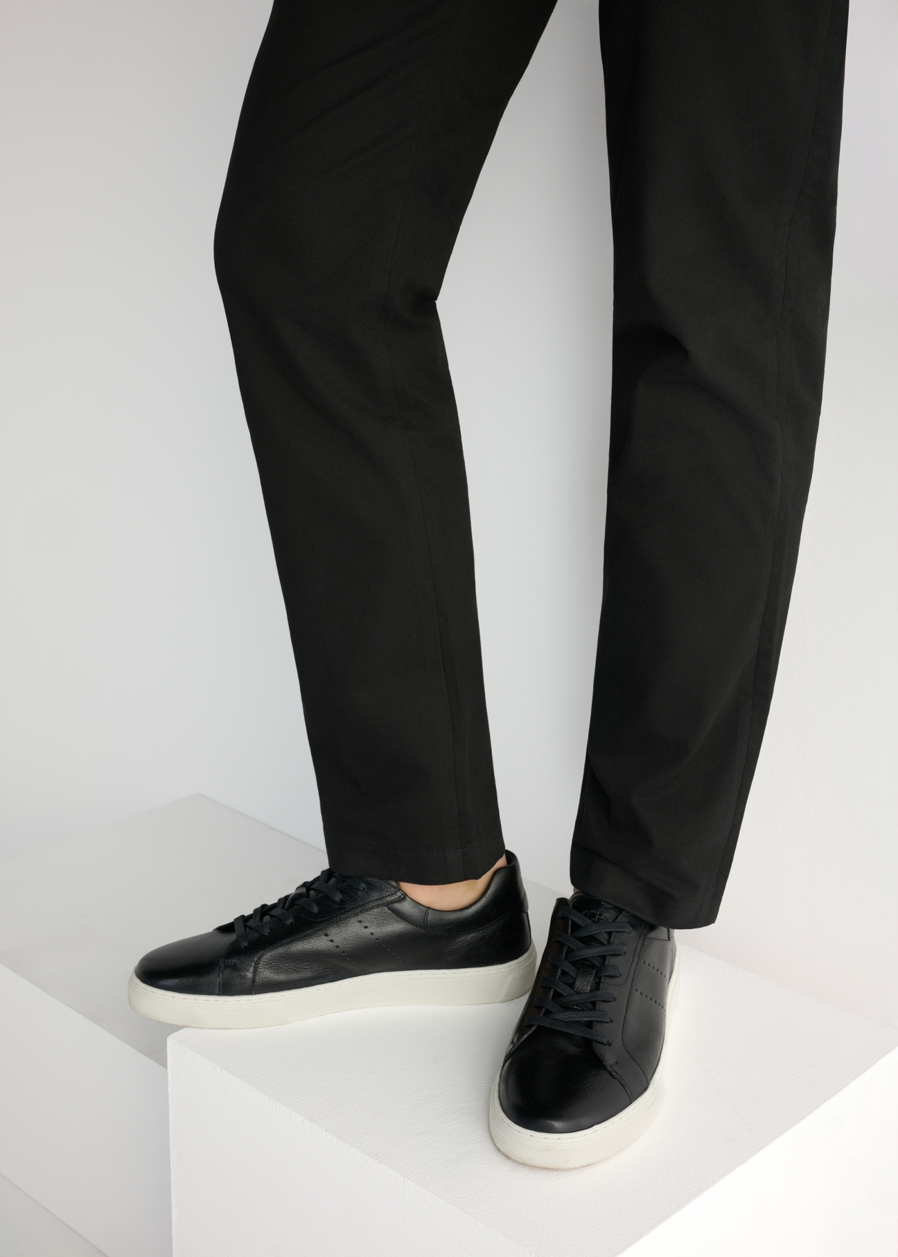 Čierne pánske kožené tenisky BUTYM-0486-99(W26), bočný pohľad na produkt na modeli, viditeľná polovica siluety.