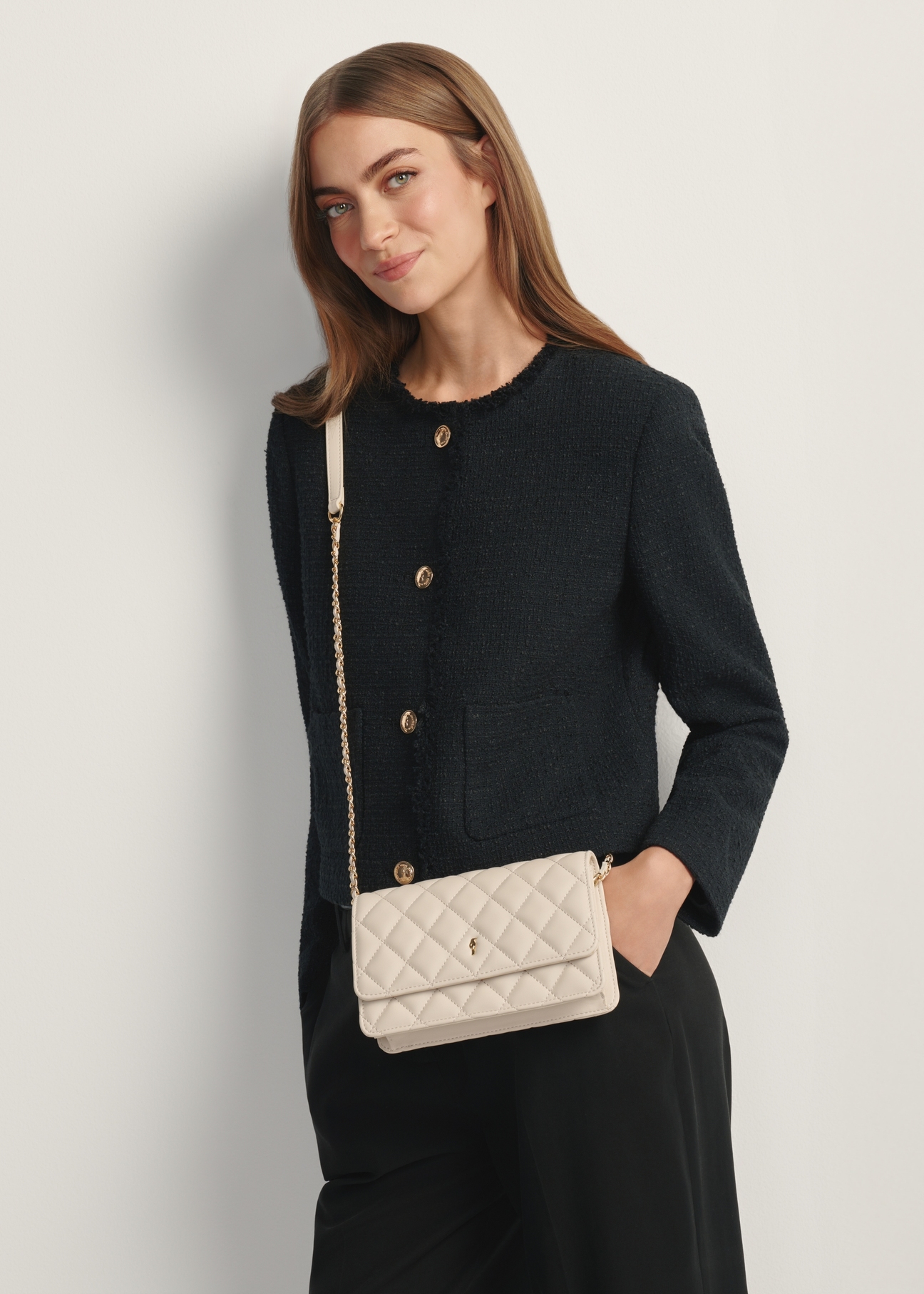 Krémová malá prešívaná dámska kabelka TOREC-1033-0B(W26), pohľad na produkt na ramene modelky. Viditeľná polovica siluety.