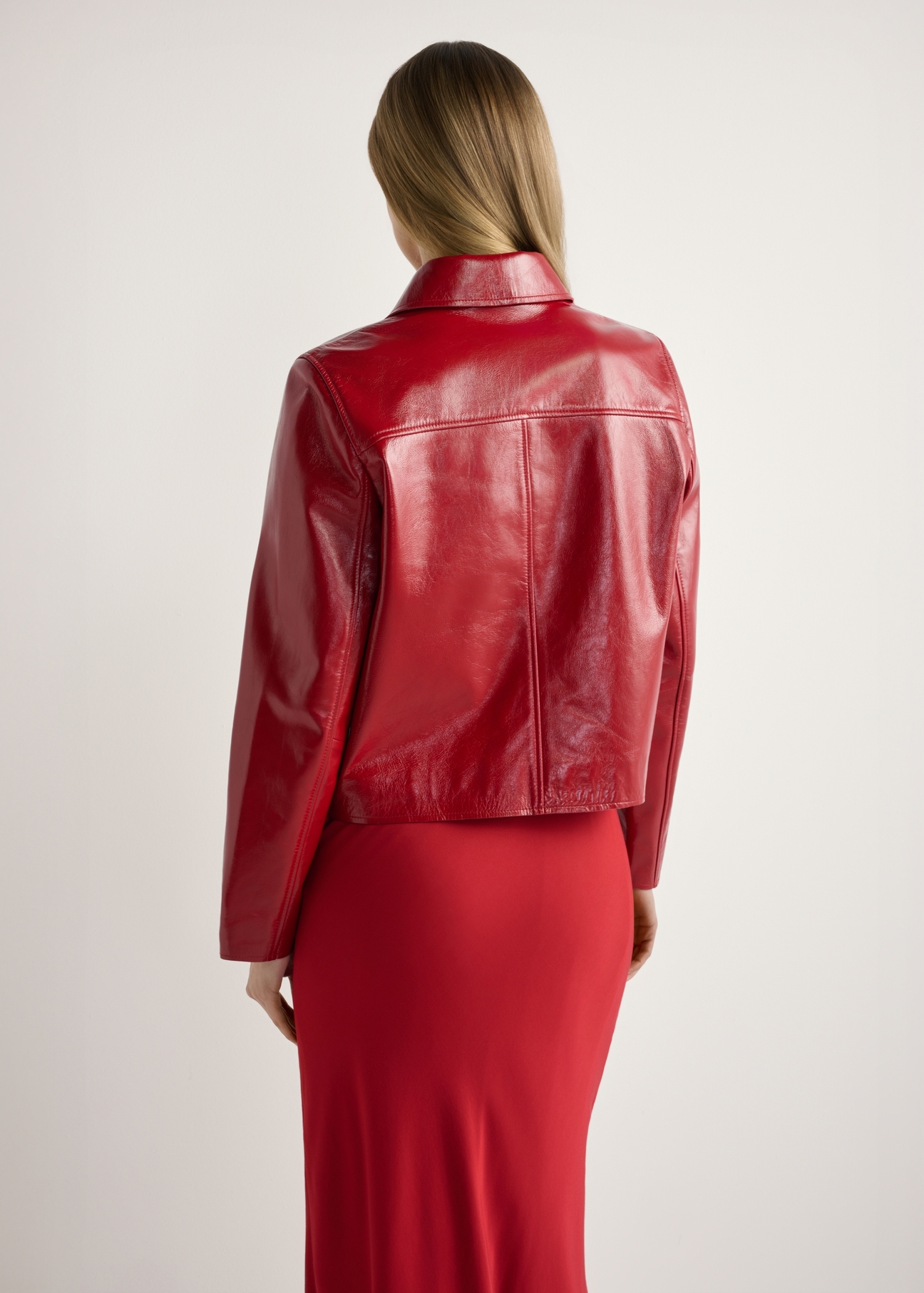 Červená krátka dámska bunda KURDS-0612-4B(W26), pohľad na produkt zozadu na modelke, viditeľná polovica siluety.