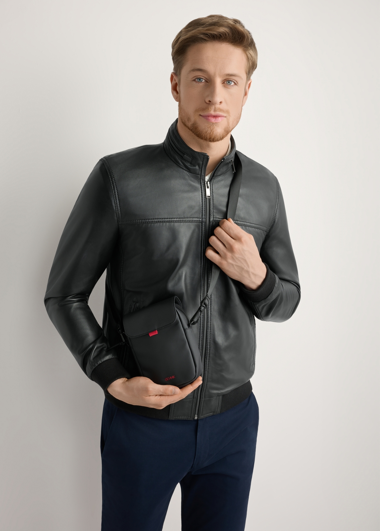 Pánska malá čierna taška cez rameno TORMN-0399-9J(W26), pohľad na produkt na siluete modelu, na svetlom pozadí.