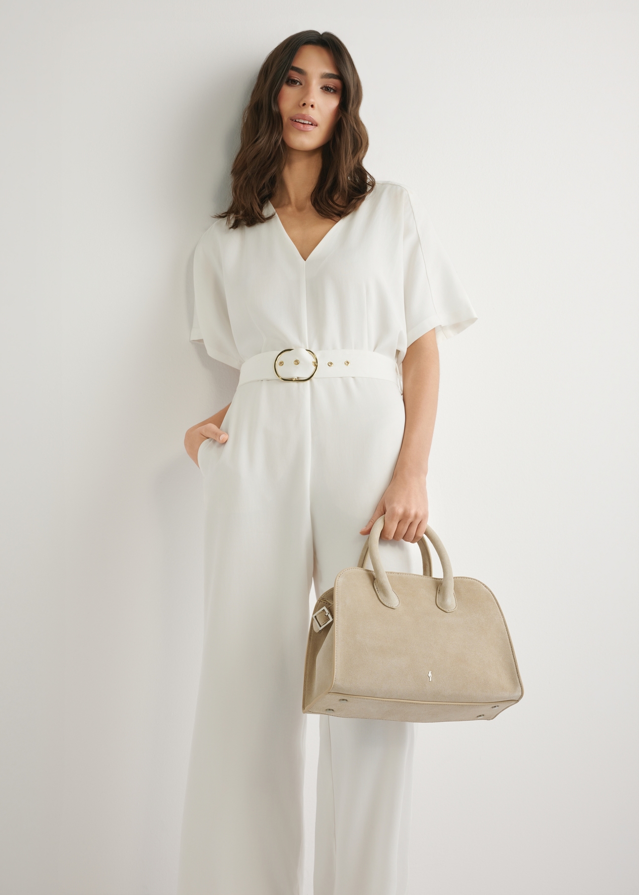 Dámska semišová kabelka krémovej farby TORES-1295-0B(W26), pohľad na produkt v ruke modelky. Viditeľná polovica siluety.