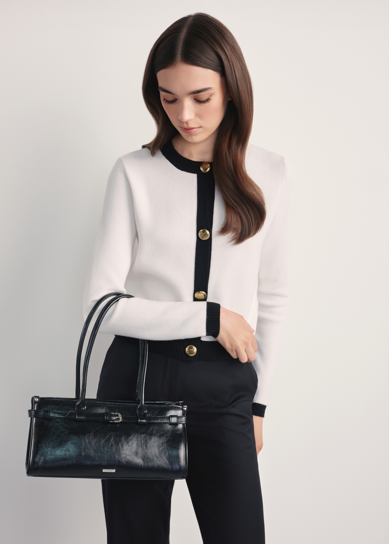 Elegantná čierna dámska kabelka TOREC-1065-99(Z25) - pohľad spredu na produkt na modelke, na bielom pozadí. Viditeľná silueta po kolená.