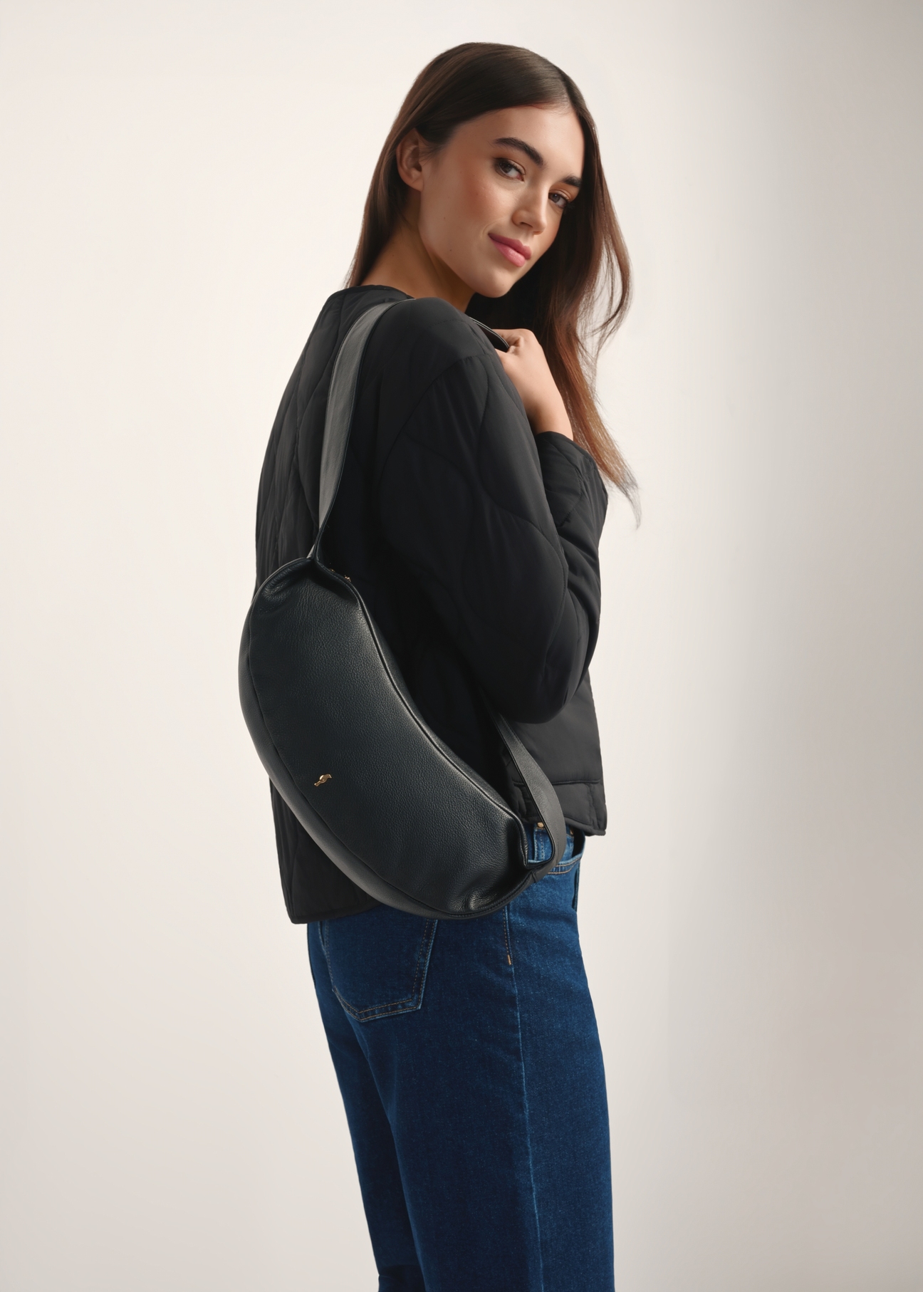 Čierna kožená kabelka v bagetovom štýle TORES-1238-99(W26), pohľad spredu na produkt na modelke, viditeľná polovica siluety.