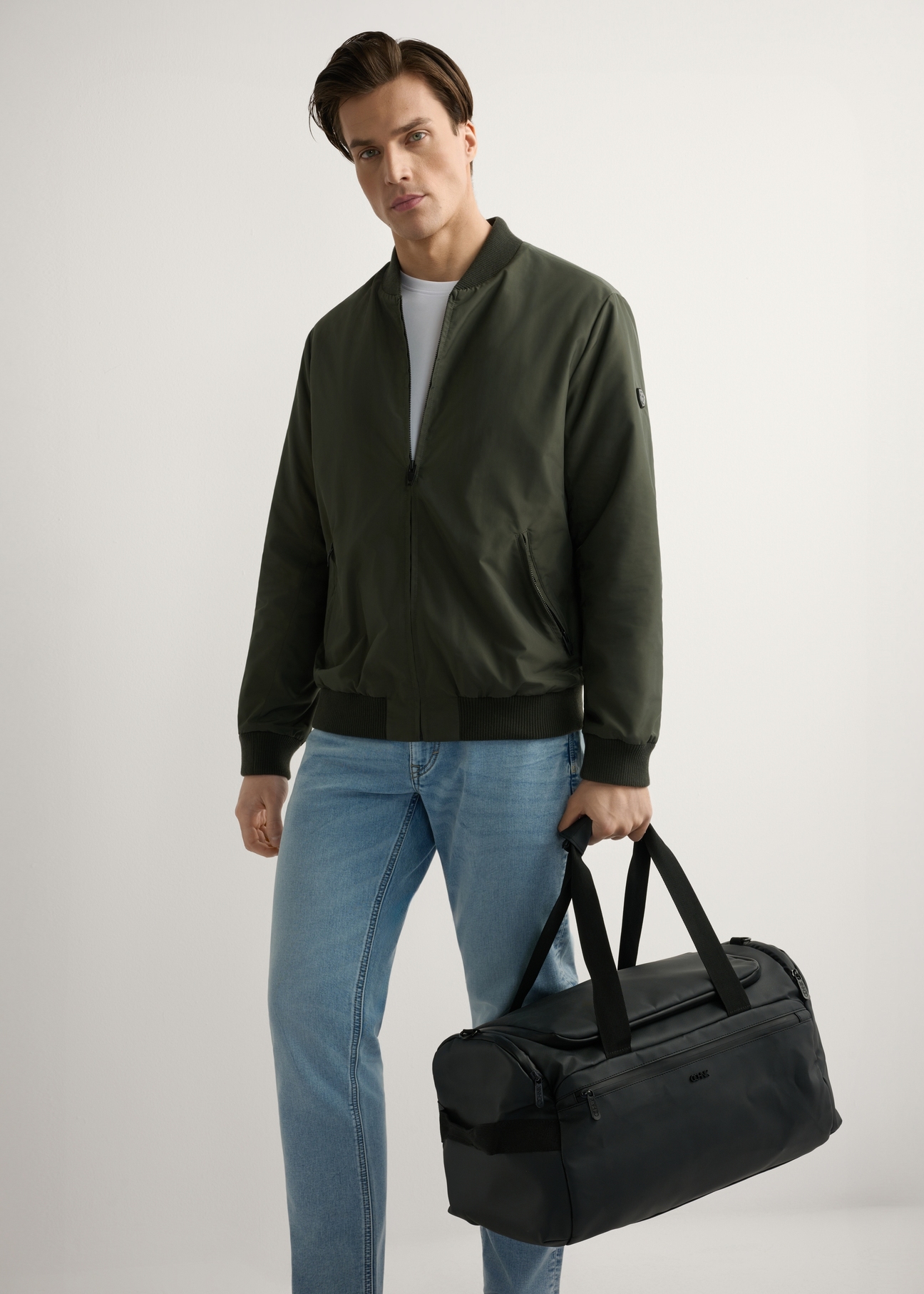 Čierna cestovná taška TORMN-0412-99(W26), pohľad na produkt v ruke modelky. Viditeľné celé telo.